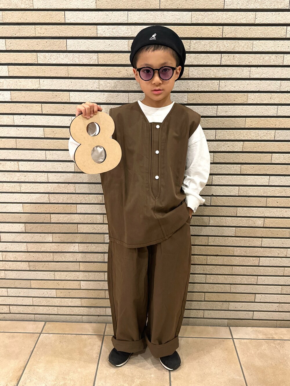 ブラウン系のベスト、ホワイト系のTシャツ/カットソー、ブラック系のスニーカーを着用したキッズの秋コーディネートの2枚目の写真