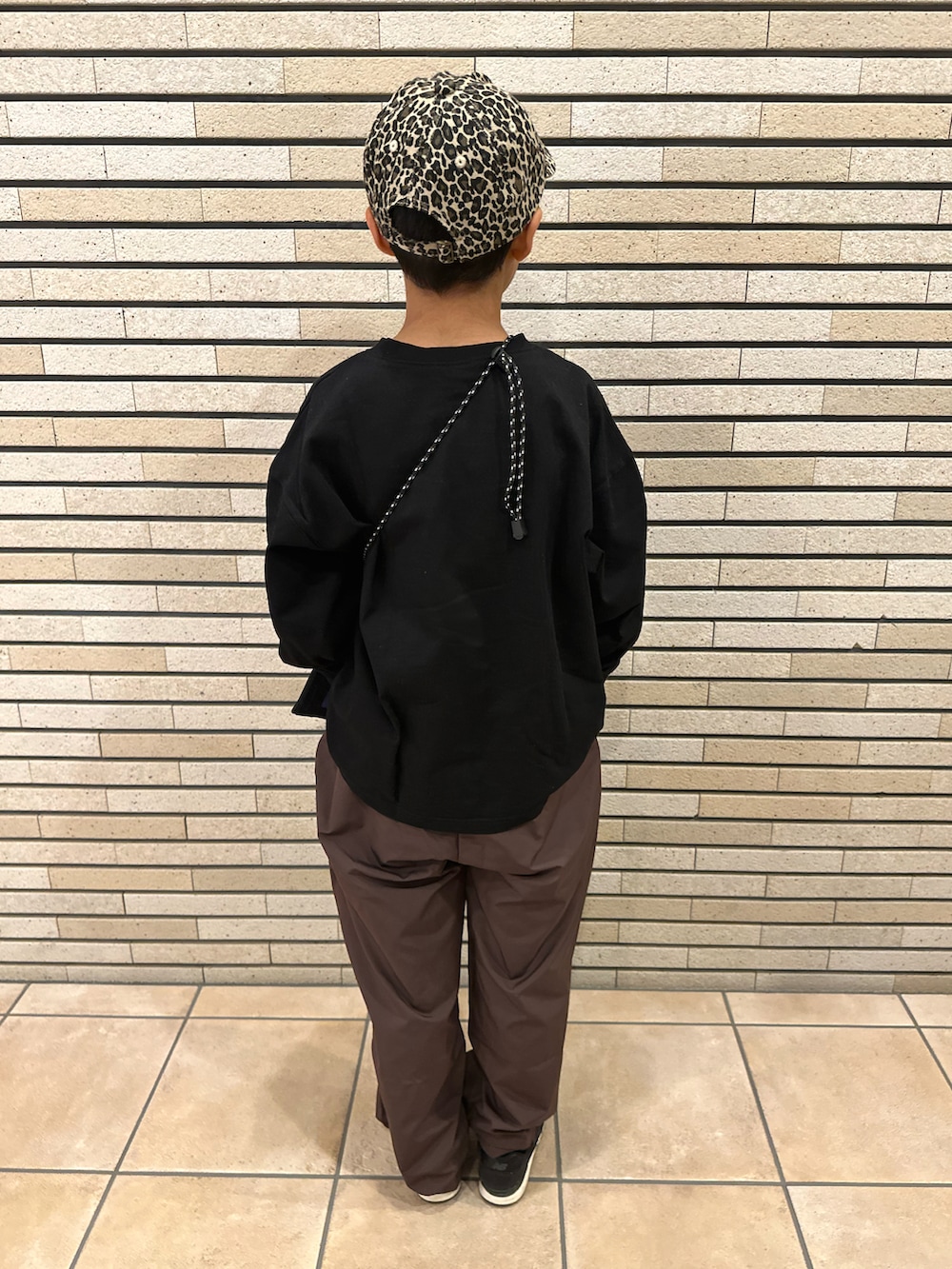 ブラック系のTシャツ/カットソー、ブラウン系のパンツ、ブラック系のスニーカーを着用したキッズの秋コーディネートの3枚目の写真