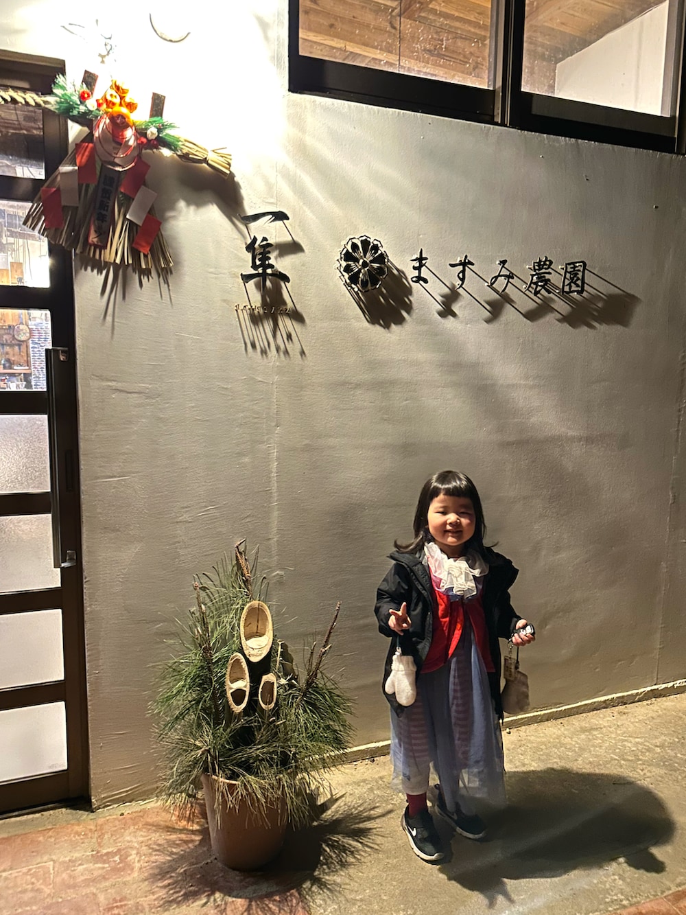 レッド系のワンピース、ブラック系のスニーカー、ブラック系のマウンテンパーカーを着用したキッズの春コーディネートの4枚目の写真