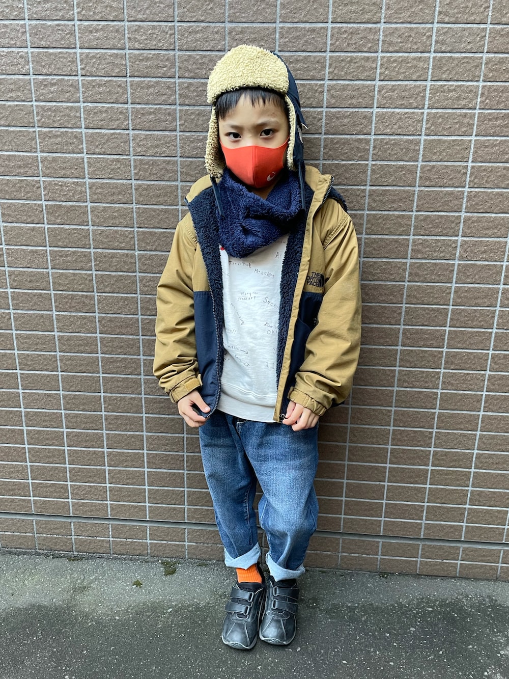 ベージュ系のブルゾン、ホワイト系のスウェット、ブルー系のデニムパンツを着用したキッズの冬コーディネートの2枚目の写真