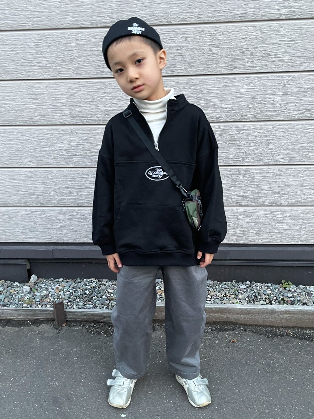 ブラック系のスウェット、ホワイト系のトップス、グレー系のチノパンツを着用したキッズの秋コーディネートの4枚目の写真