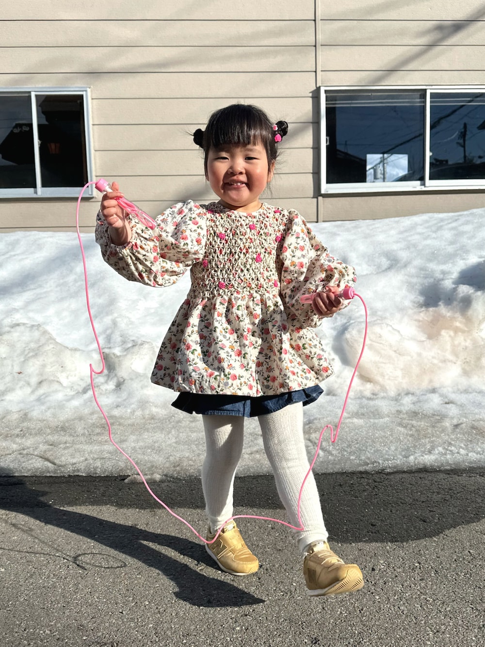 ピンク系のチュニック、ブルー系のデニムパンツ、ゴールド系のスニーカーを着用したキッズの春コーディネートの3枚目の写真