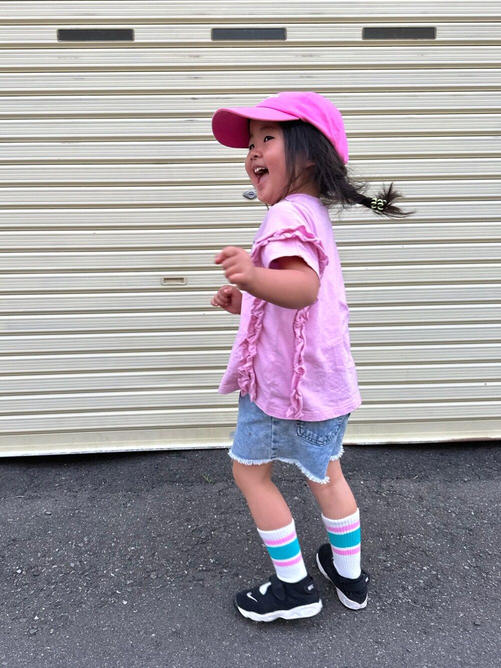 ピンク系のTシャツ/カットソー、ブラック系のスニーカー、ブルー系のデニムパンツを着用したキッズの夏コーディネートの3枚目の写真