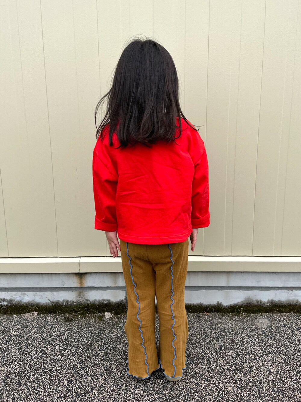レッド系のカーディガン/ボレロ、ブラウン系のパンツ、レッド系のスニーカーを着用したキッズの春コーディネートの3枚目の写真