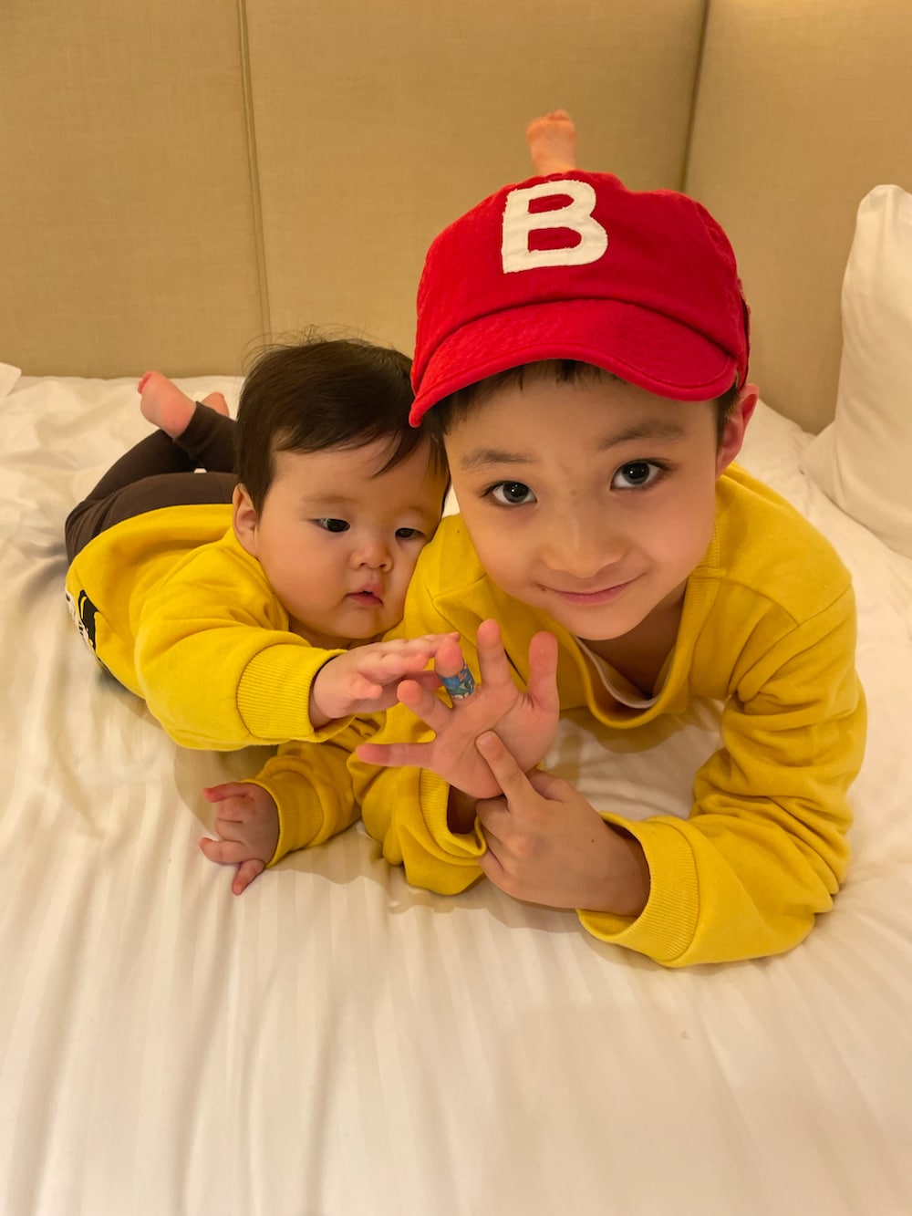 イエロー系のスウェット、ブラック系のその他パンツ、ホワイト系のパーカーを着用したキッズの秋コーディネートの3枚目の写真