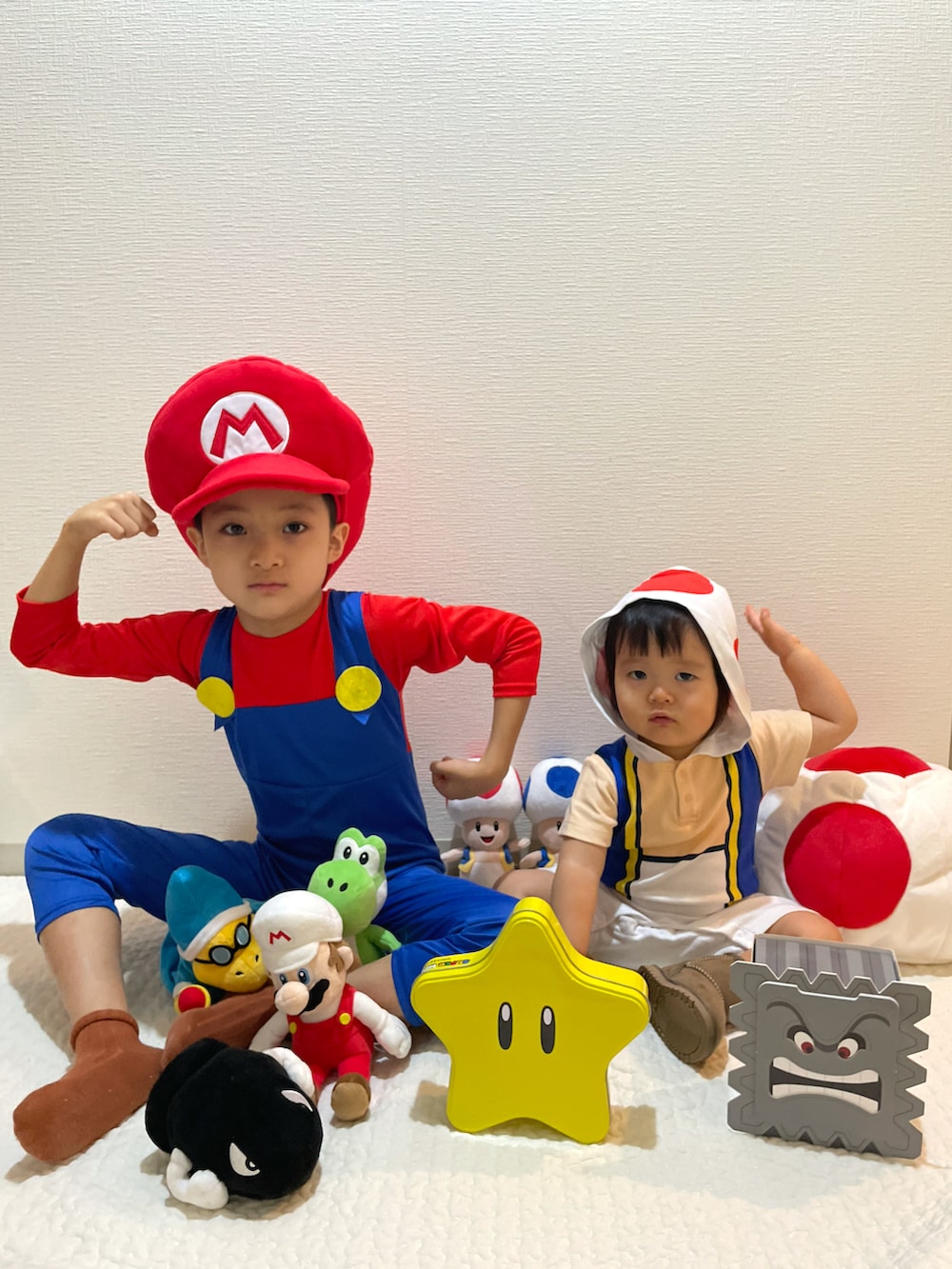 レッド系のオールインワン・サロペット、レッド系のキャスケット、ホワイト系のロンパースを着用したキッズの秋コーディネートの2枚目の写真