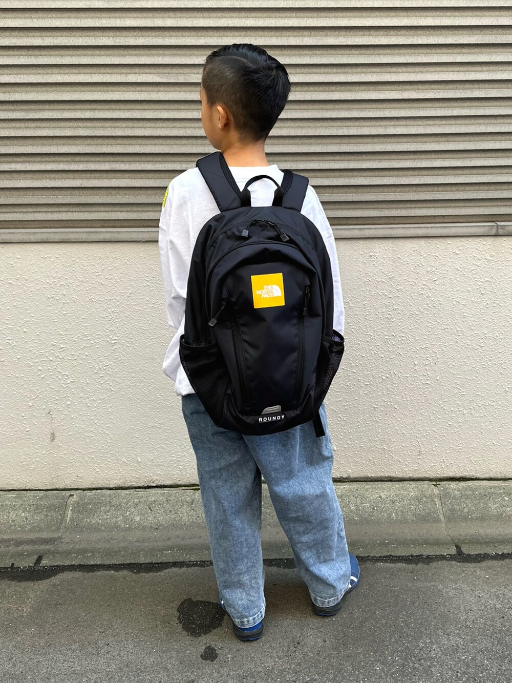 ホワイト系のTシャツ/カットソー、ブルー系のデニムパンツ、ブラック系のバックパック/リュックを着用したキッズの秋コーディネートの4枚目の写真