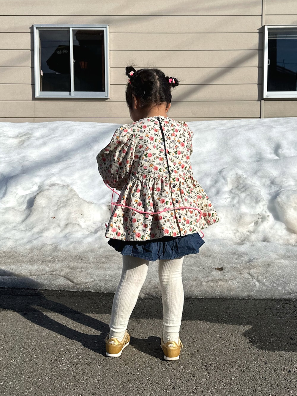 ピンク系のチュニック、ブルー系のデニムパンツ、ゴールド系のスニーカーを着用したキッズの春コーディネートの4枚目の写真