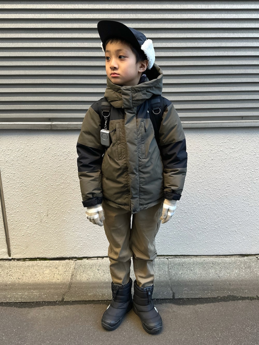 グリーン系のダウンジャケット/コート、ベージュ系のチノパンツ、ブラック系のブーツを着用したキッズの冬コーディネートの3枚目の写真