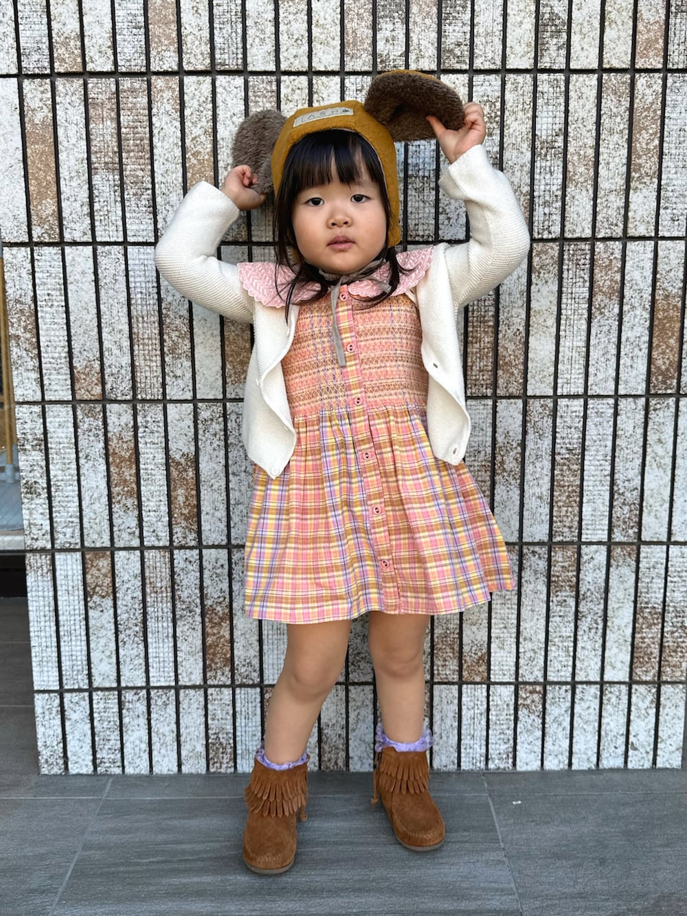 ホワイト系のカーディガン/ボレロ、ピンク系のチュニック、ブラウン系のブーツを着用したキッズの冬コーディネートの2枚目の写真