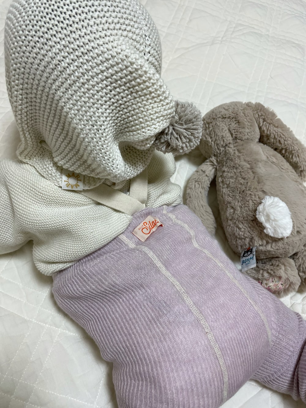 ホワイト系のカーディガン/ボレロ、グレー系のニットキャップ/ビーニー、パープル系のレギンス/スパッツを着用したキッズの冬コーディネートの3枚目の写真