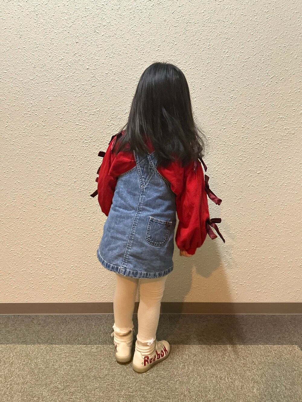 レッド系のスウェット、ブルー系のジャンパースカート、レッド系のスニーカーを着用したキッズの春コーディネートの3枚目の写真