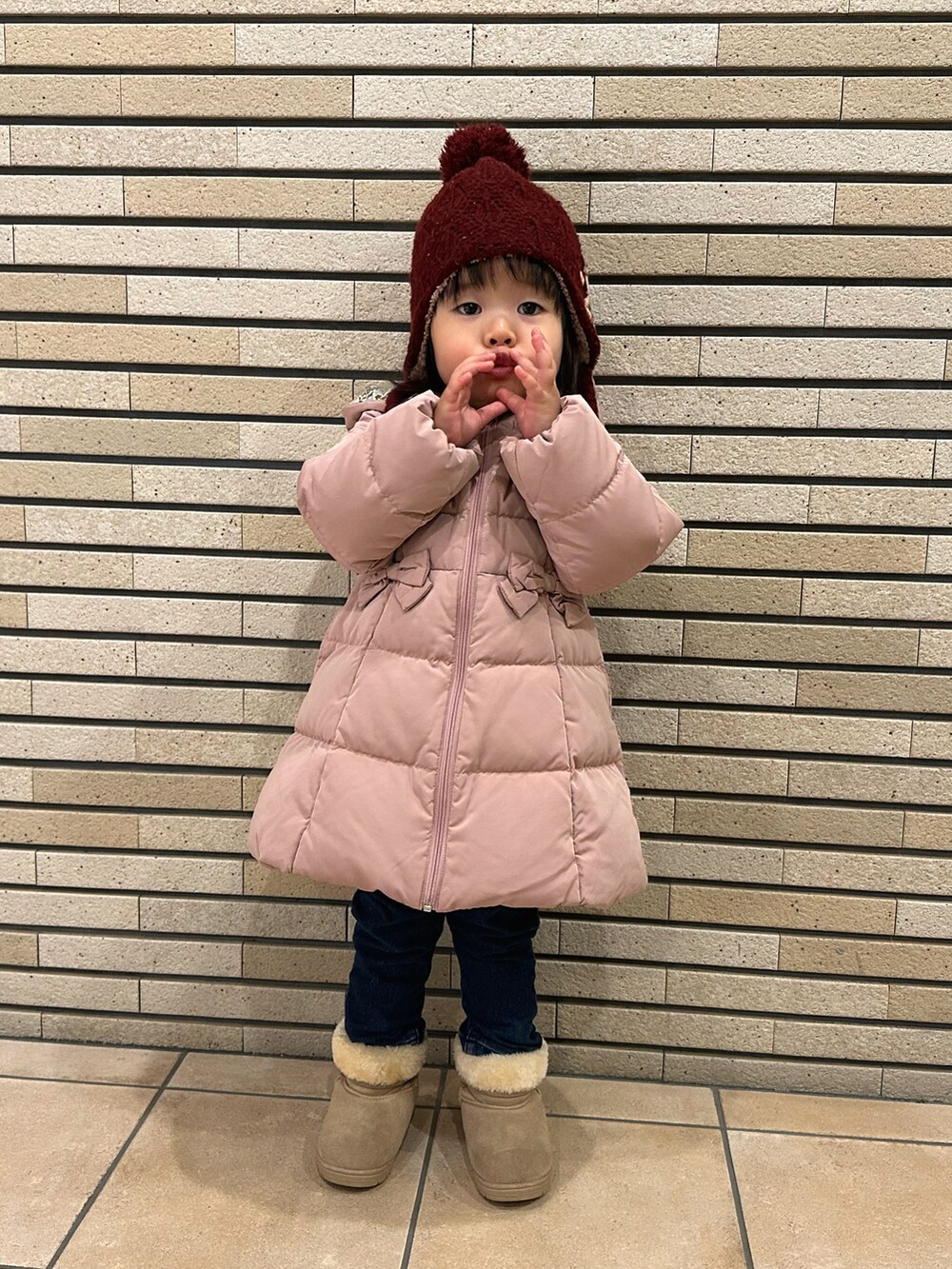 ピンク系のダウンジャケット/コート、ブルー系のその他パンツ、ベージュ系のブーツを着用したキッズの冬コーディネートの2枚目の写真