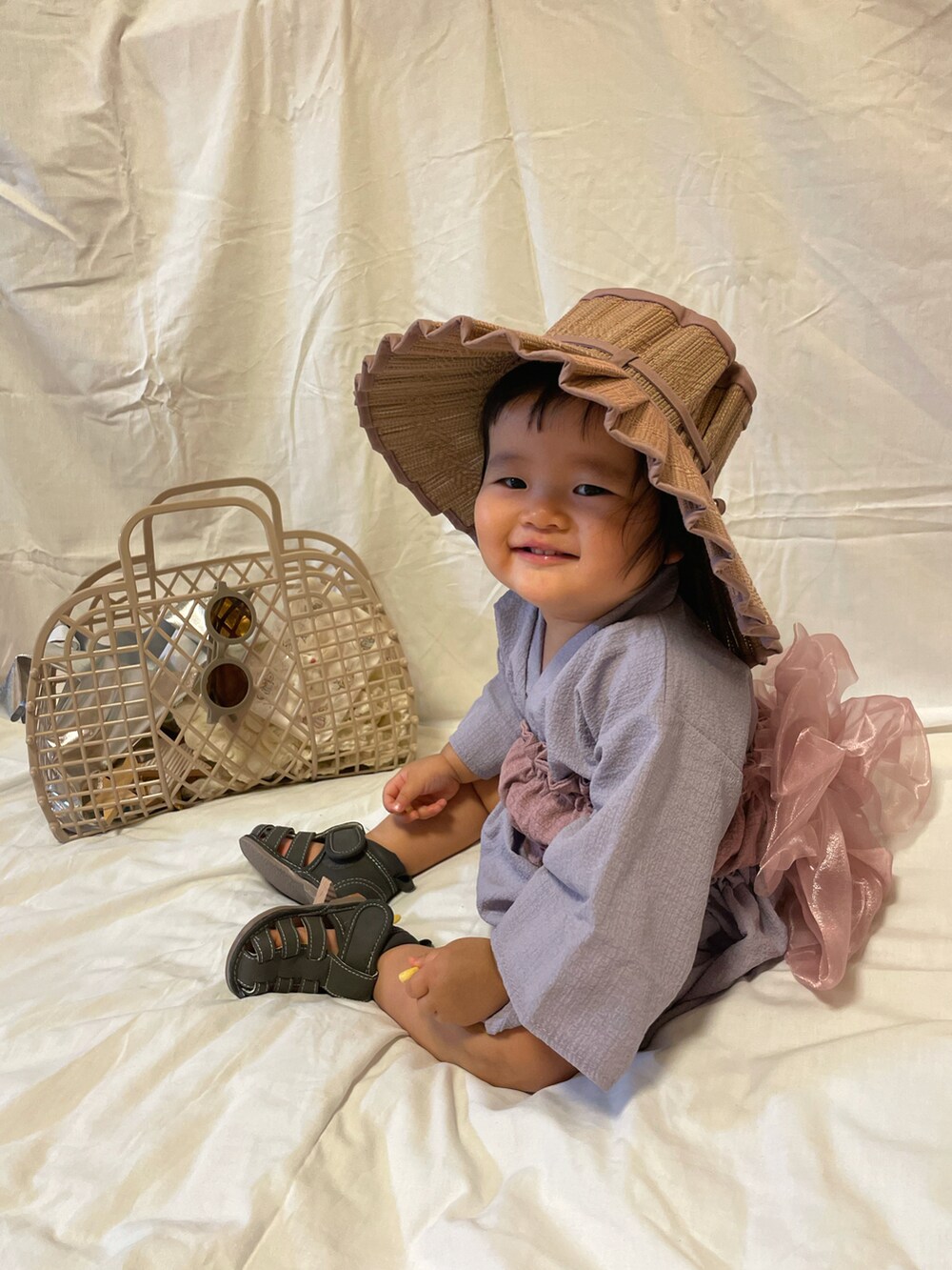 グレー系のサンダル、ベージュ系のバッグ、パープル系の帽子を着用したキッズの夏コーディネートの2枚目の写真