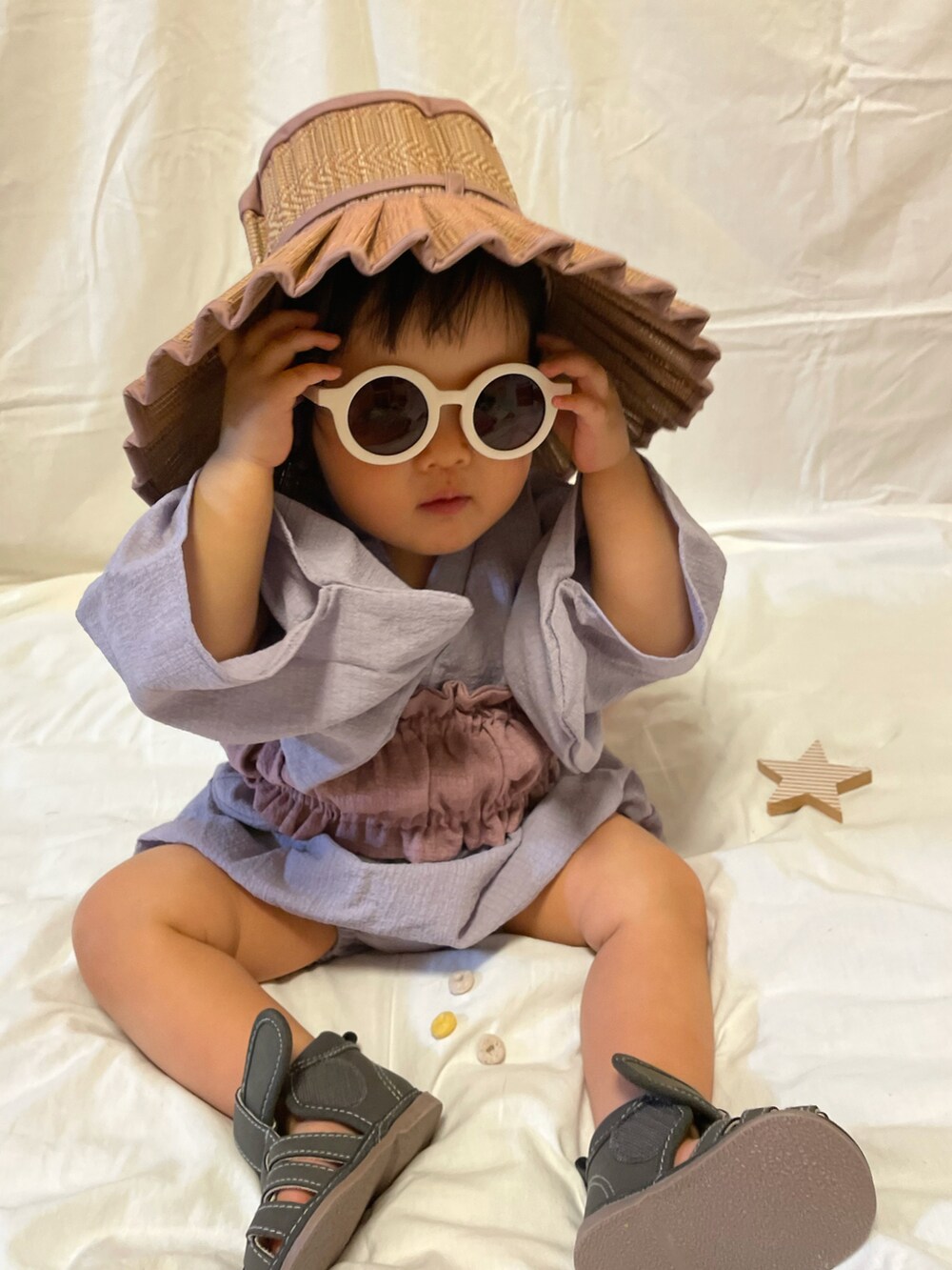 グレー系のサンダル、ベージュ系のバッグ、パープル系の帽子を着用したキッズの夏コーディネートの3枚目の写真