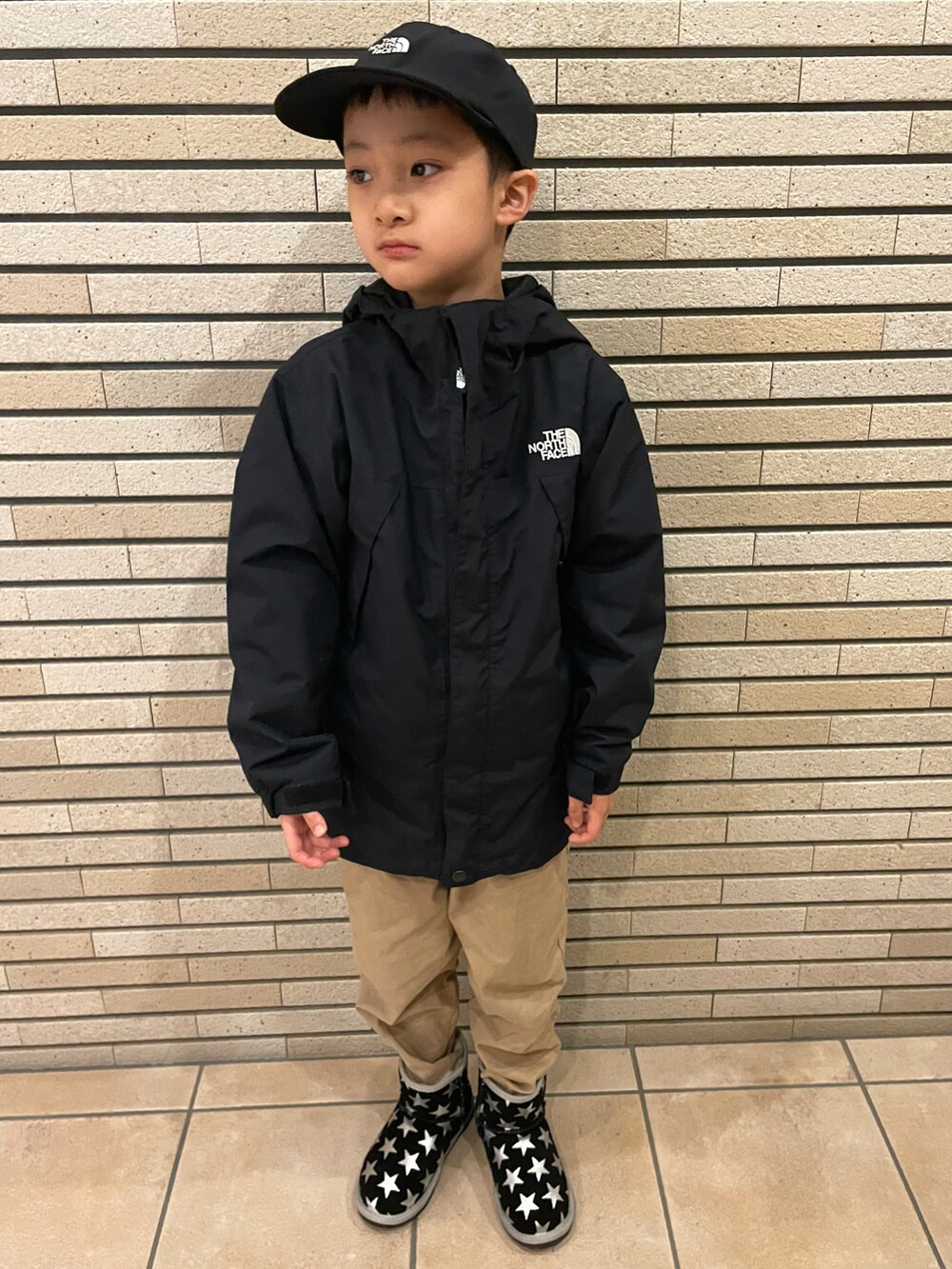 ブラウン系のスウェット、ブラック系のナイロンジャケット、ベージュ系のその他パンツを着用したキッズの秋コーディネートの2枚目の写真