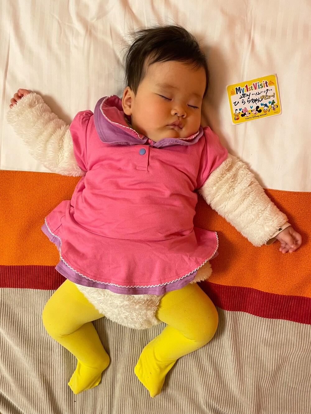 ピンク系のTシャツ/カットソー、ベージュ系のダウンジャケット/コート、ホワイト系のスニーカーを着用したキッズの春コーディネートの2枚目の写真