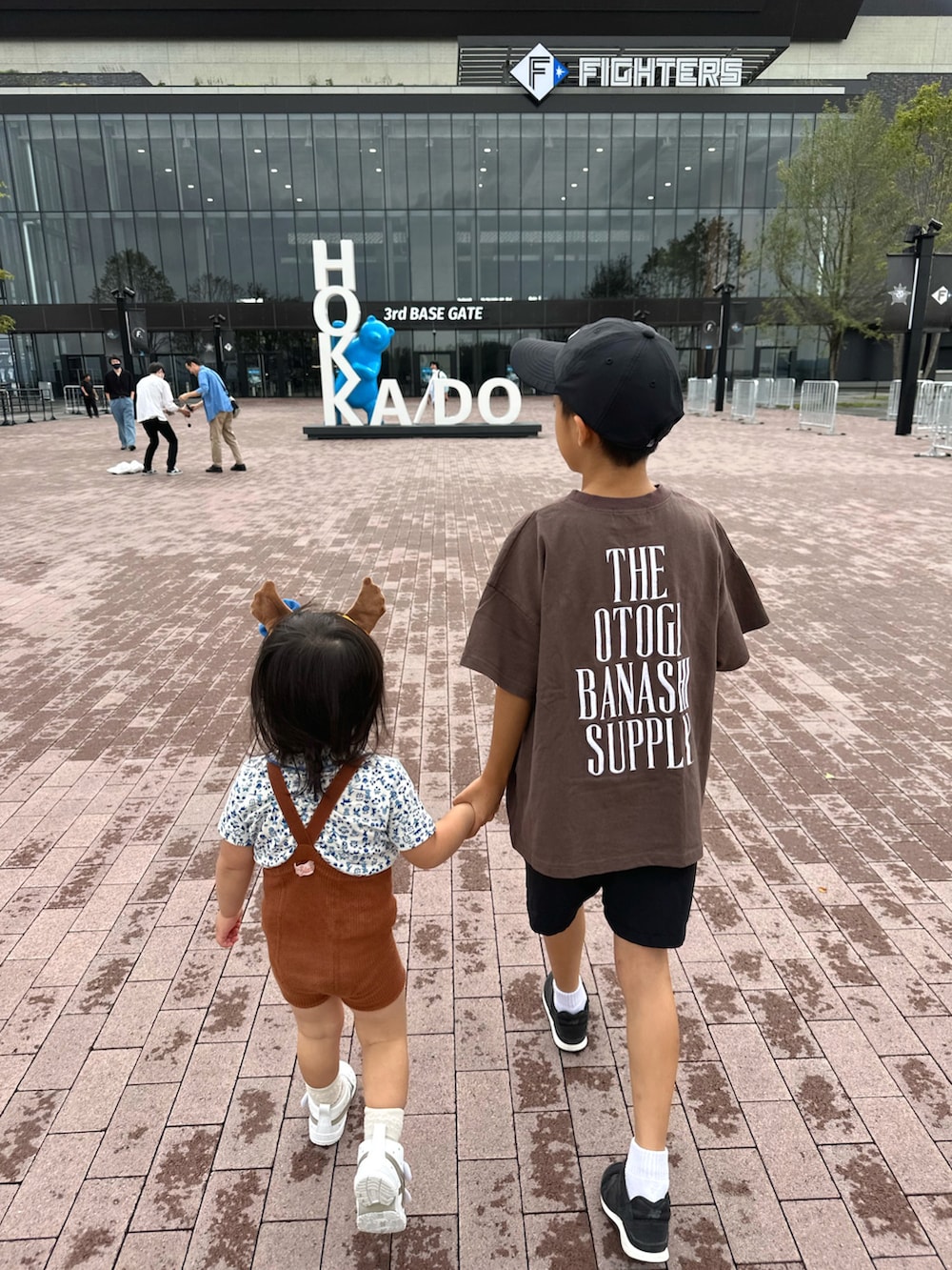 ブラウン系のTシャツ/カットソー、ブラック系のパンツ、ブラック系のスニーカーを着用したキッズの秋コーディネートの2枚目の写真