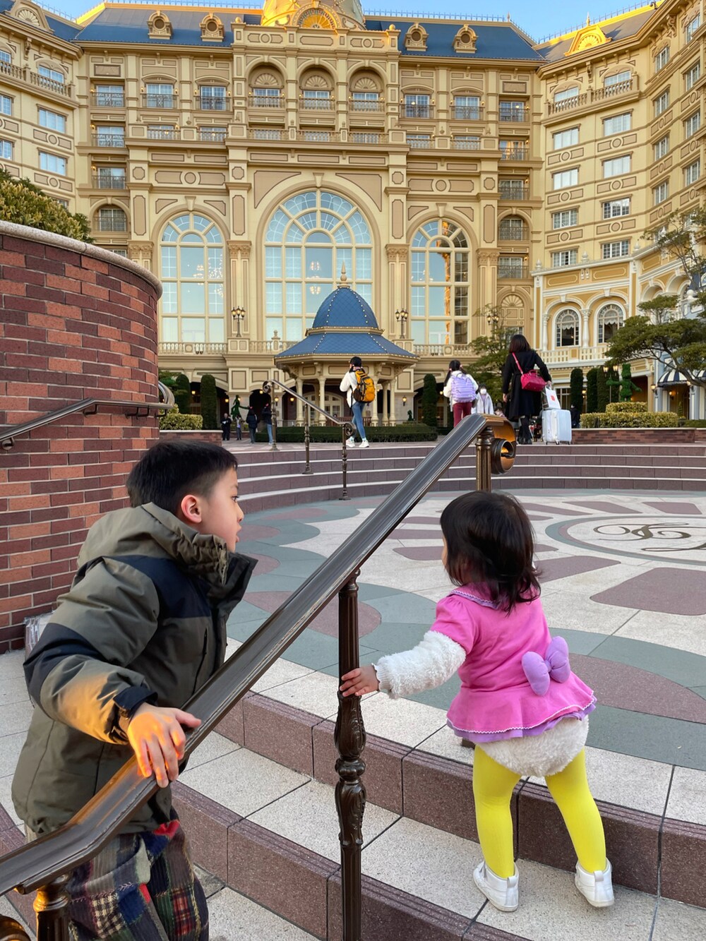 ピンク系のTシャツ/カットソー、ベージュ系のダウンジャケット/コート、ホワイト系のスニーカーを着用したキッズの春コーディネートの4枚目の写真