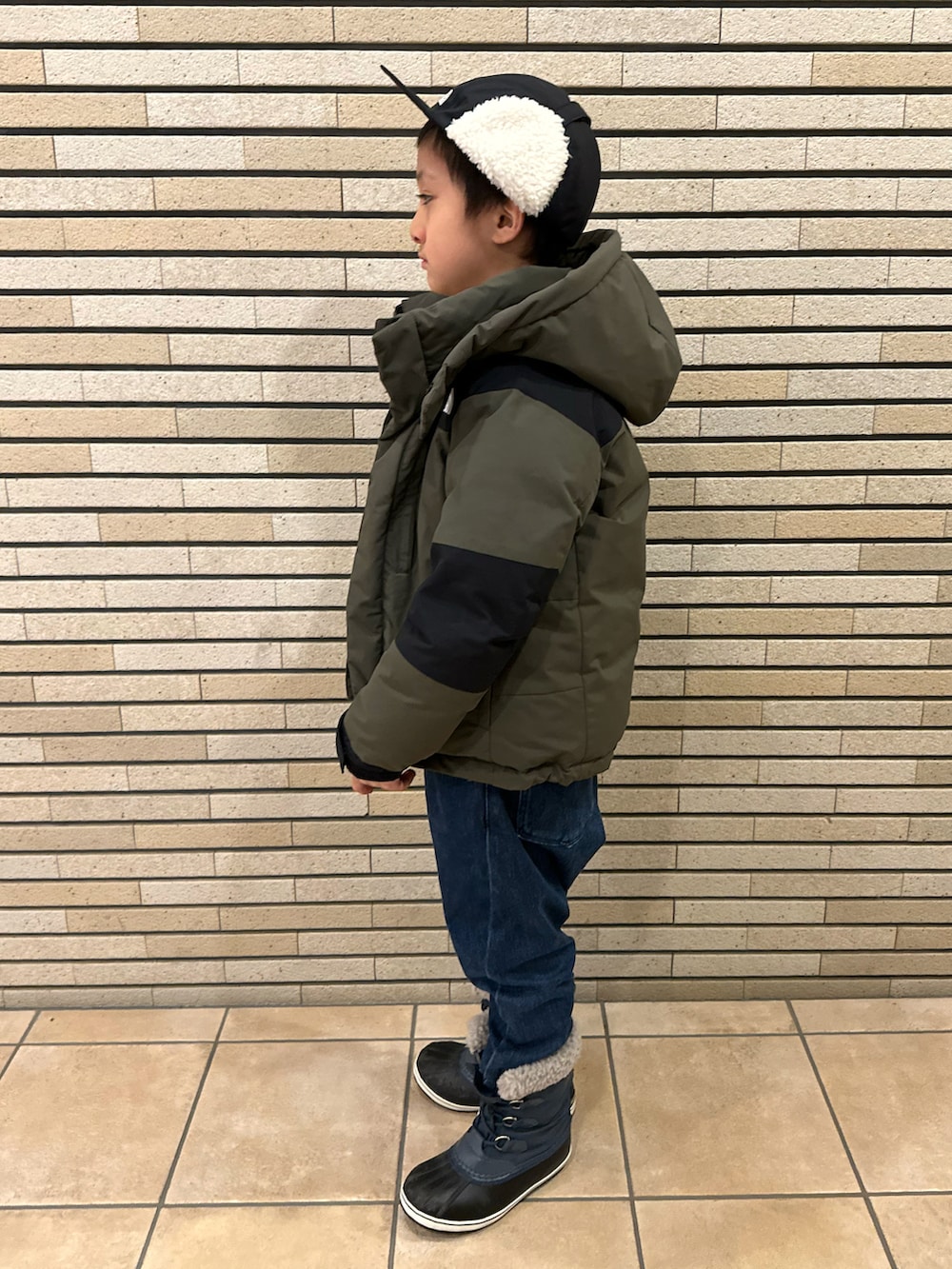グリーン系のダウンジャケット/コート、ブラウン系のスウェット、ブルー系のデニムパンツを着用したキッズの冬コーディネートの2枚目の写真