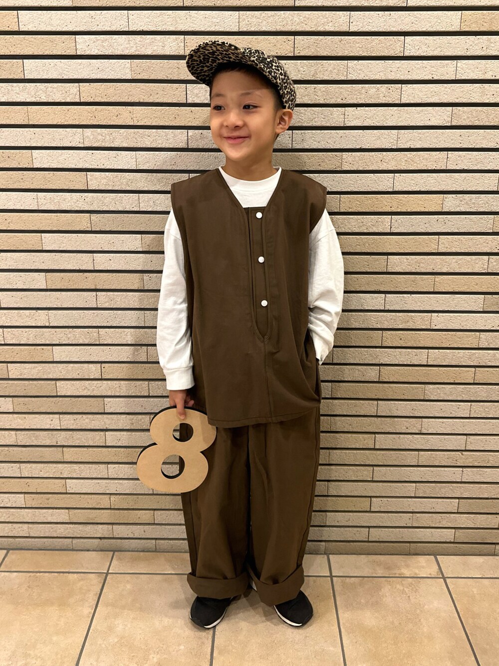 ブラウン系のベスト、ホワイト系のTシャツ/カットソー、ブラック系のスニーカーを着用したキッズの秋コーディネートの5枚目の写真