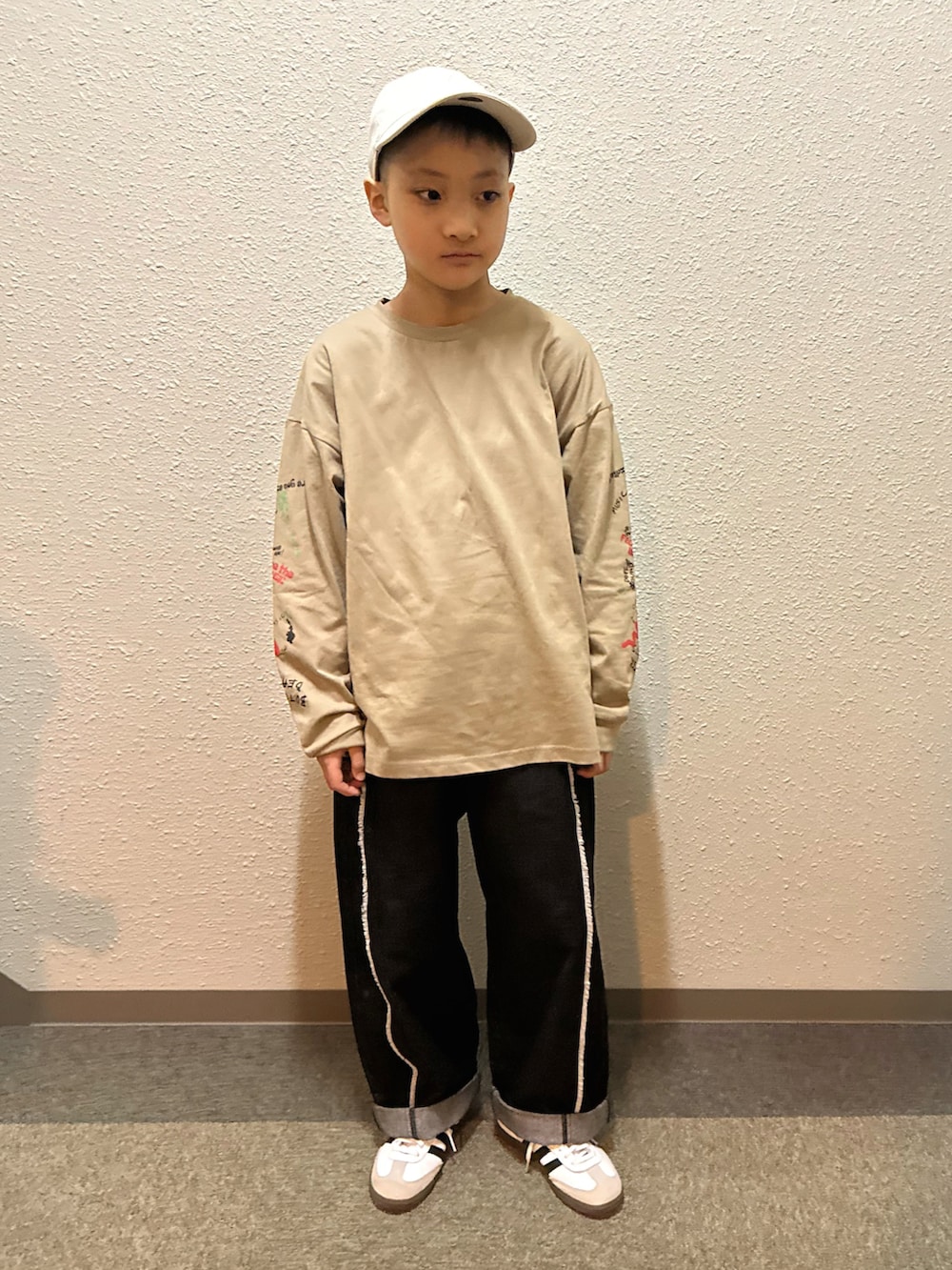 ベージュ系のTシャツ/カットソー、ブラック系のデニムパンツ、ホワイト系のスニーカーを着用したキッズの春コーディネートの4枚目の写真