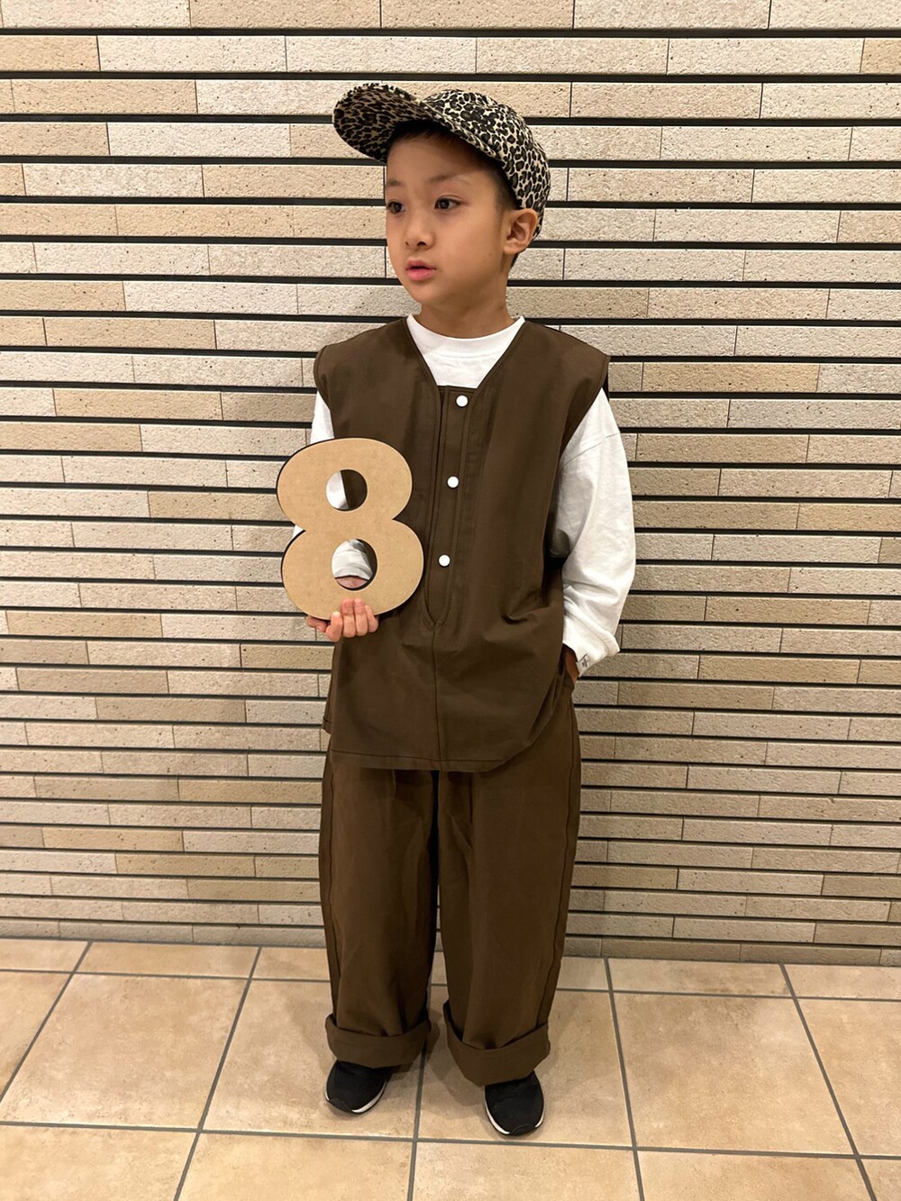 ブラウン系のベスト、ホワイト系のTシャツ/カットソー、ブラック系のスニーカーを着用したキッズの秋コーディネートの4枚目の写真