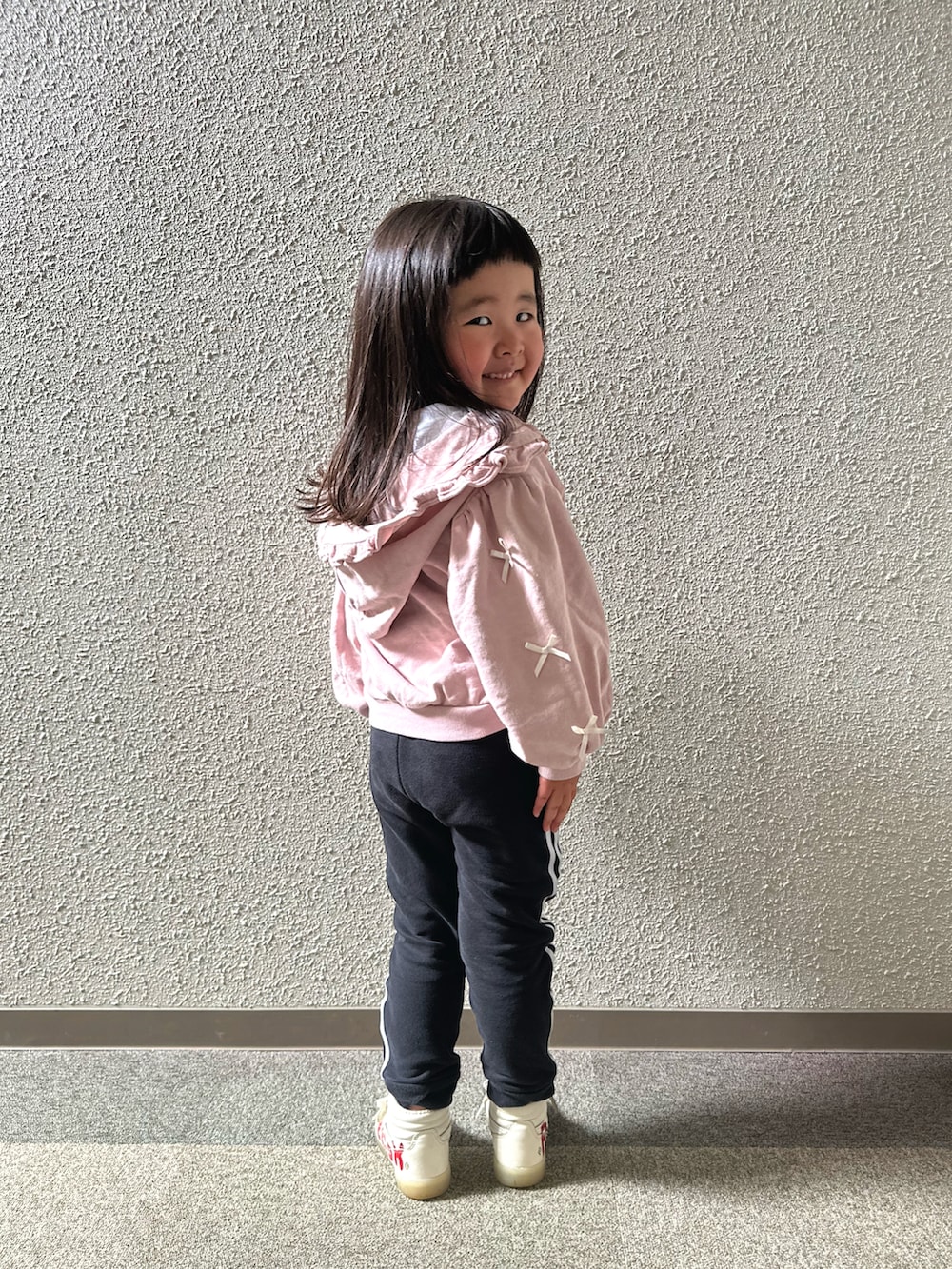 ピンク系のパーカー、ブラック系のジャージ、レッド系のスニーカーを着用したキッズの夏コーディネートの3枚目の写真