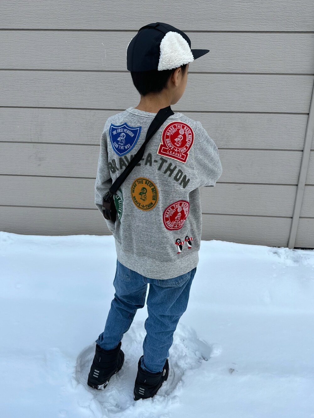 グレー系のスウェット、ブルー系のデニムパンツ、ブラック系のブーツを着用したキッズの秋コーディネートの2枚目の写真