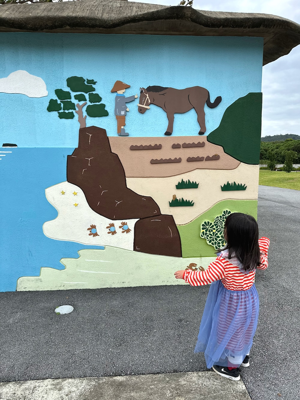 レッド系のワンピース、ブラック系のスニーカー、ブラック系のマウンテンパーカーを着用したキッズの春コーディネートの2枚目の写真