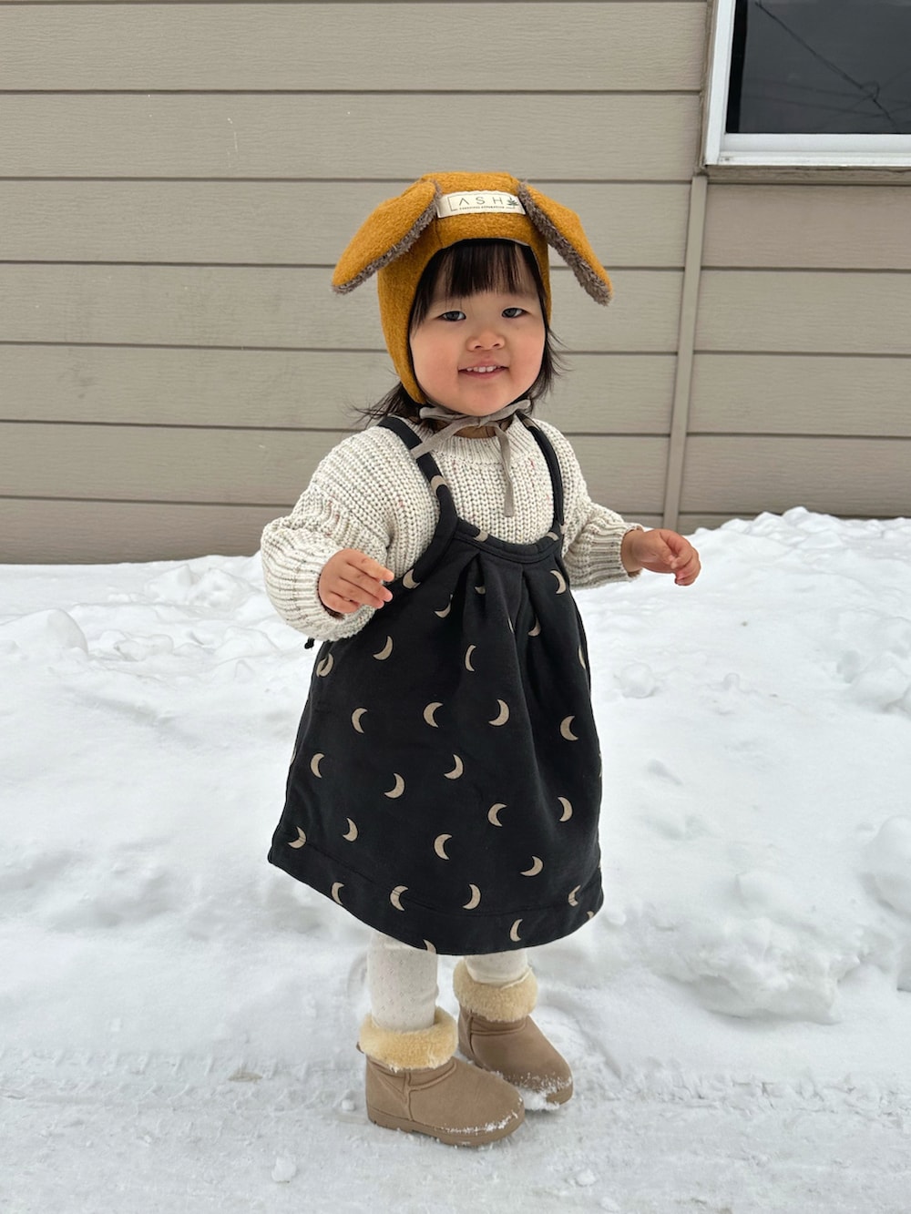 ホワイト系のニット/セーター、ブラック系のワンピース、ベージュ系のブーツを着用したキッズの冬コーディネートの3枚目の写真