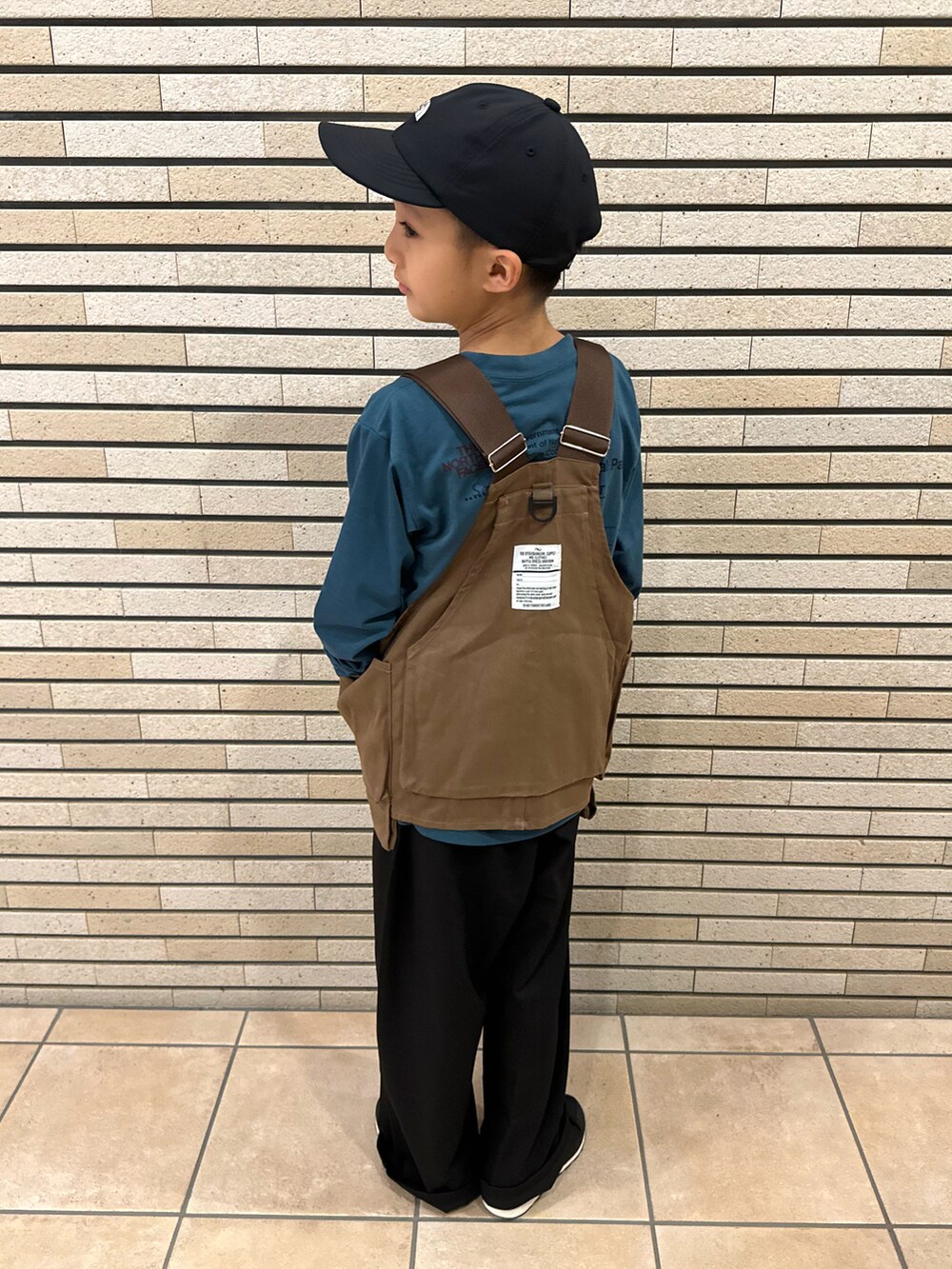 グリーン系のTシャツ/カットソー、ブラウン系のベスト、ブラック系のスラックスを着用したキッズの秋コーディネートの3枚目の写真