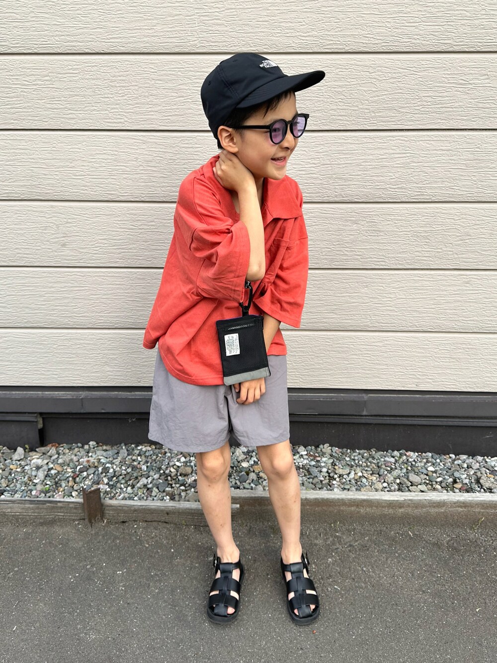 レッド系のセットアップ、ブラック系のサンダル、ブラック系のキャップを着用したキッズの夏コーディネートの3枚目の写真