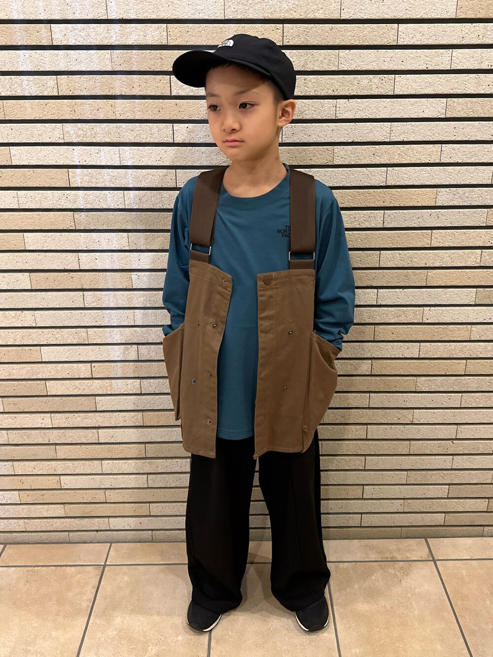 グリーン系のTシャツ/カットソー、ブラウン系のベスト、ブラック系のスラックスを着用したキッズの秋コーディネートの2枚目の写真