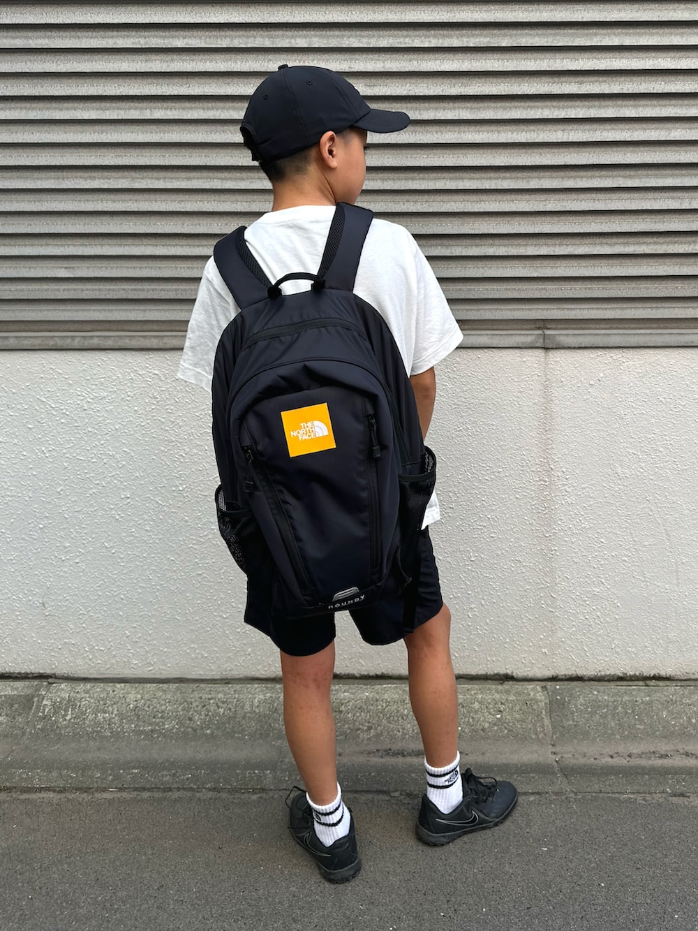ブラック系のその他パンツ、ブラック系のバックパック/リュック、ホワイト系のTシャツ/カットソーを着用したキッズの夏コーディネートの3枚目の写真