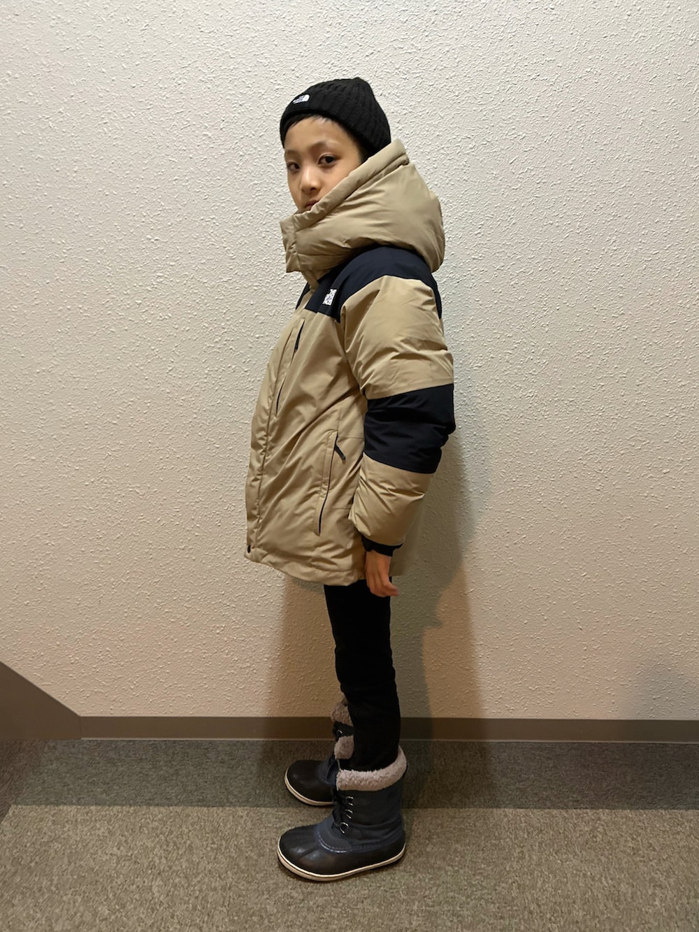 ベージュ系のダウンジャケット/コート、ブラック系のパンツ、ブルー系のブーツを着用したキッズの冬コーディネートの3枚目の写真
