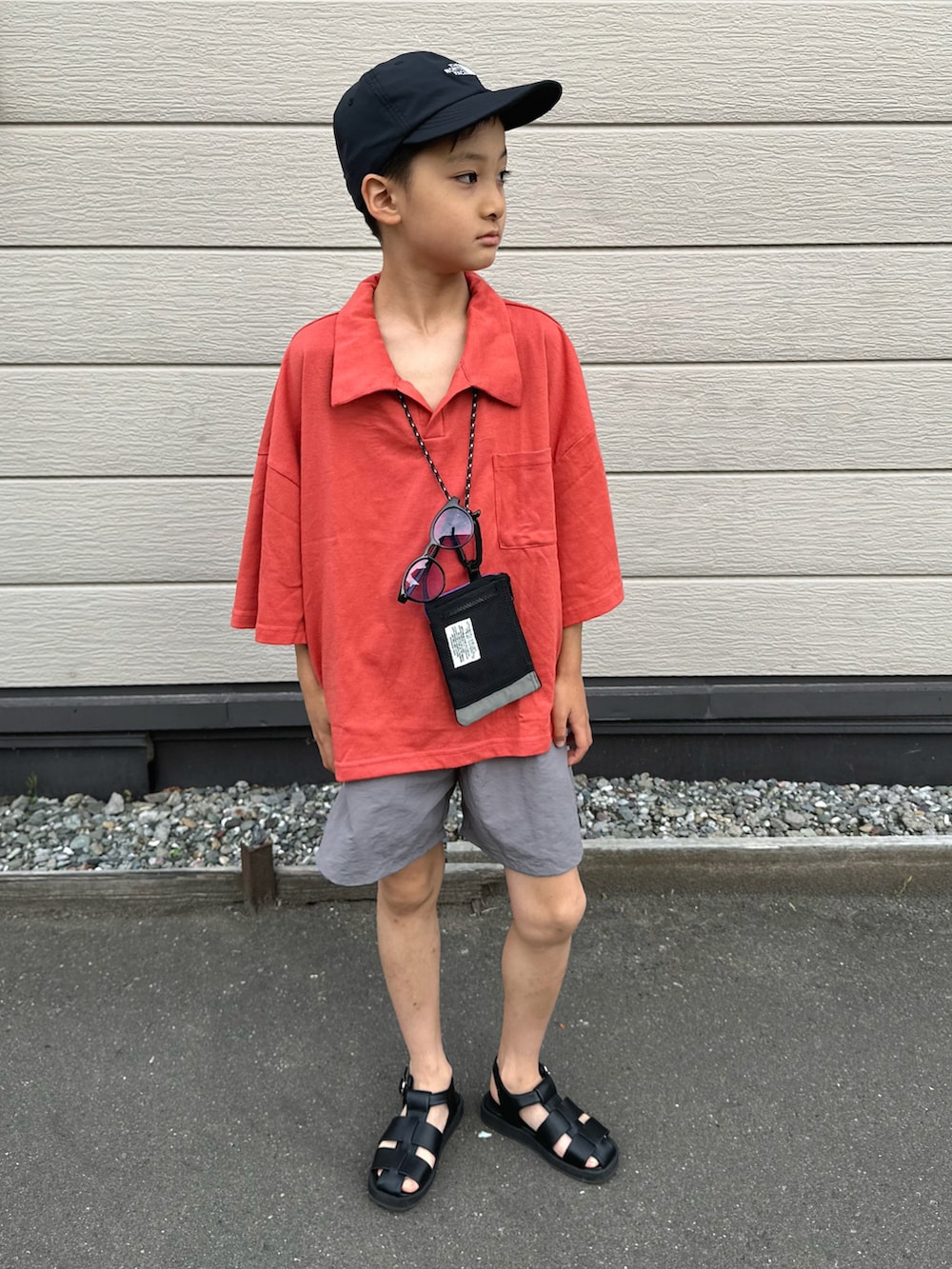 レッド系のセットアップ、ブラック系のサンダル、ブラック系のキャップを着用したキッズの夏コーディネートの2枚目の写真