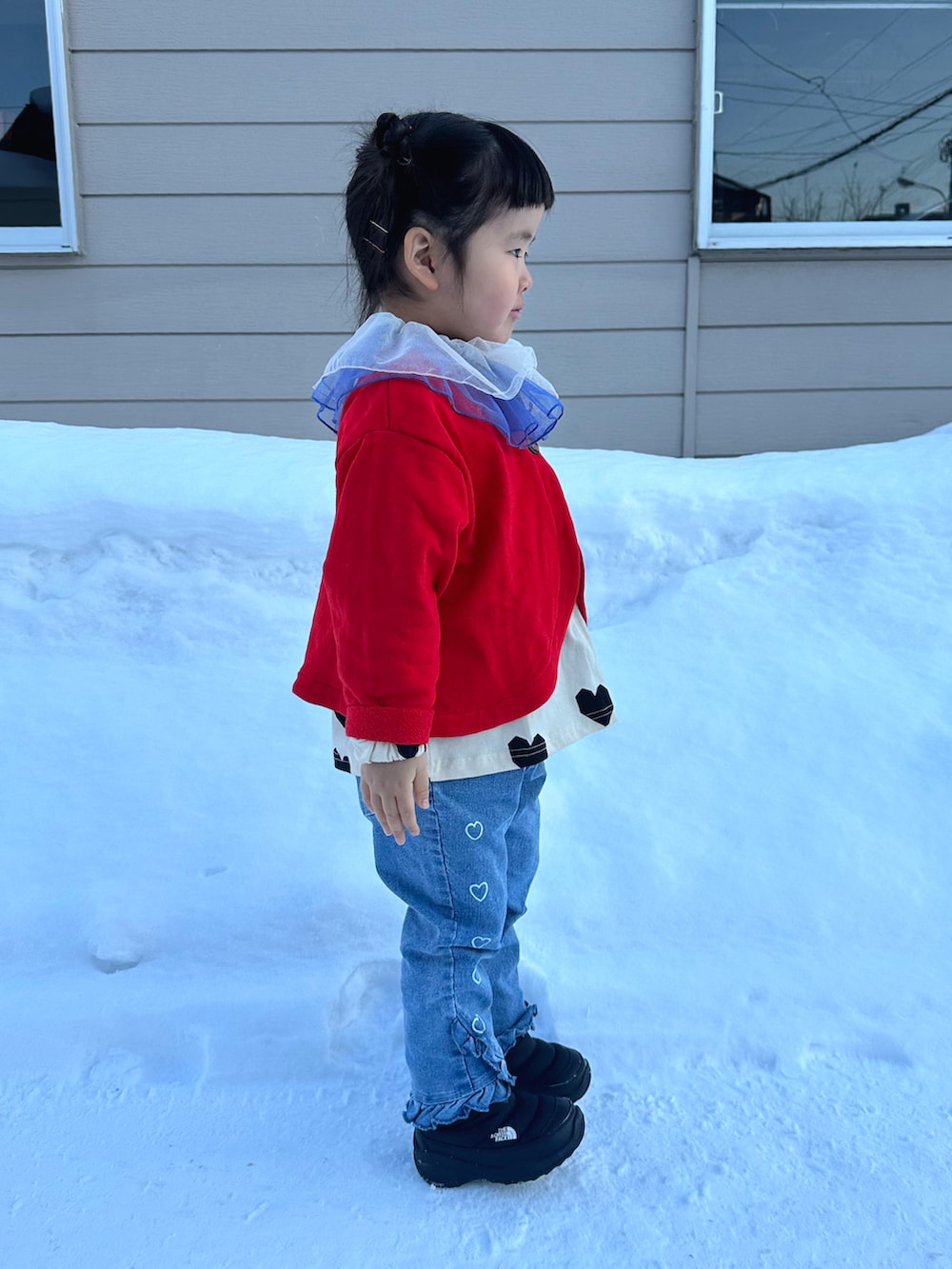 ホワイト系のTシャツ/カットソー、レッド系のカーディガン/ボレロ、ブルー系のデニムパンツを着用したキッズの冬コーディネートの3枚目の写真