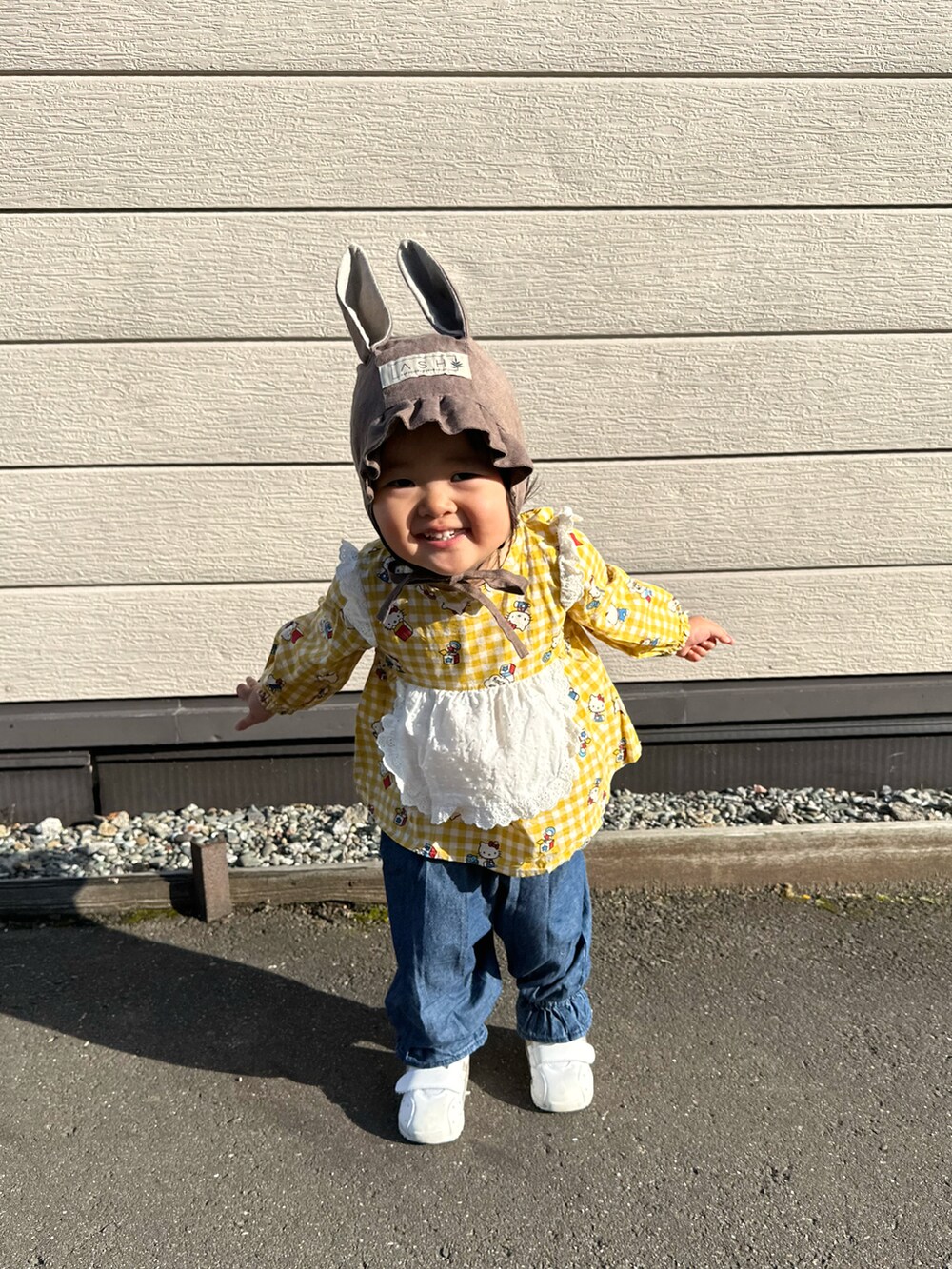 イエロー系のチュニック、ブルー系のデニムパンツ、ホワイト系のスニーカーを着用したキッズの秋コーディネートの4枚目の写真