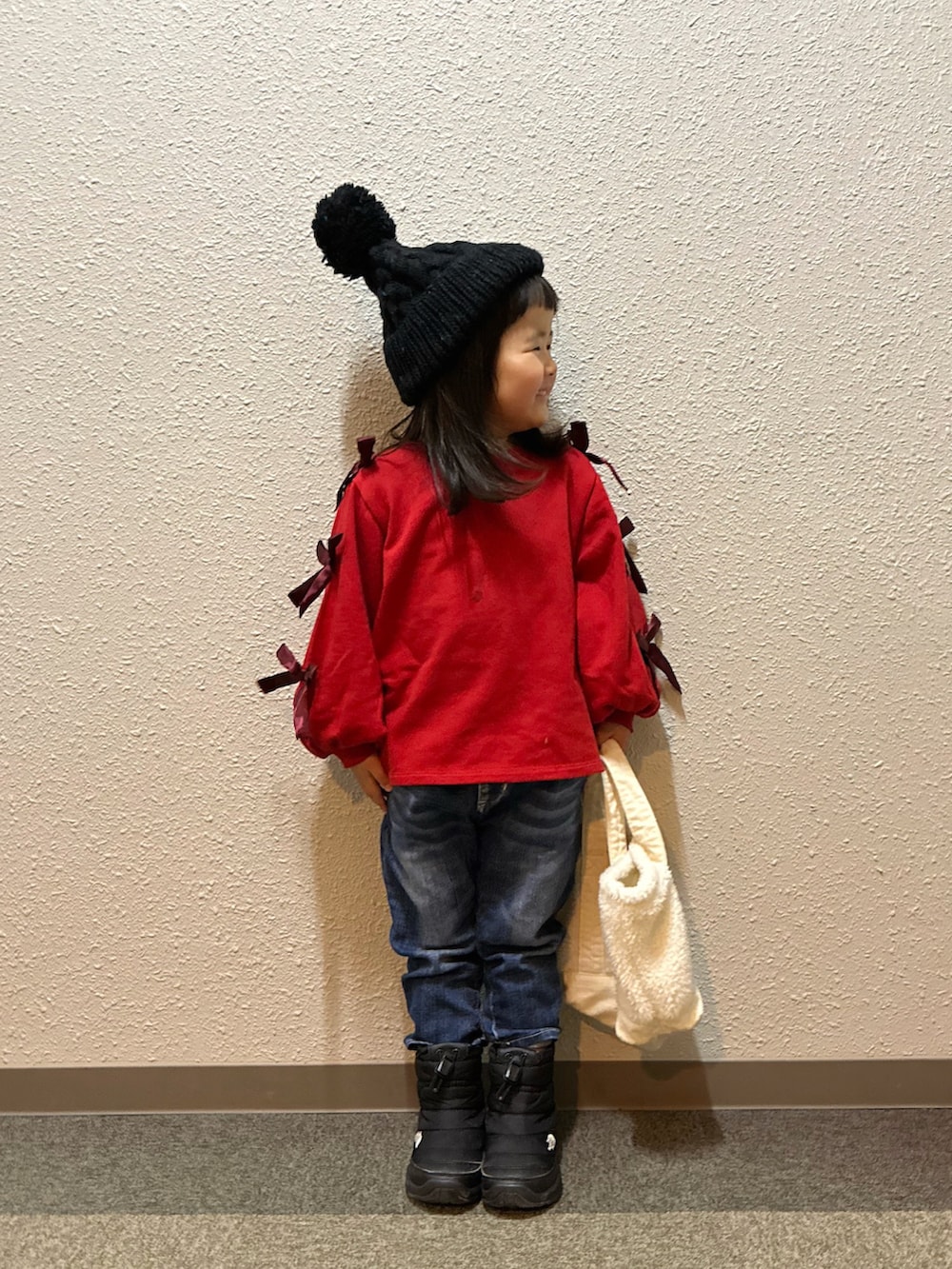 レッド系のスウェット、ブルー系のデニムパンツ、ブラック系のブーツを着用したキッズの冬コーディネートの3枚目の写真