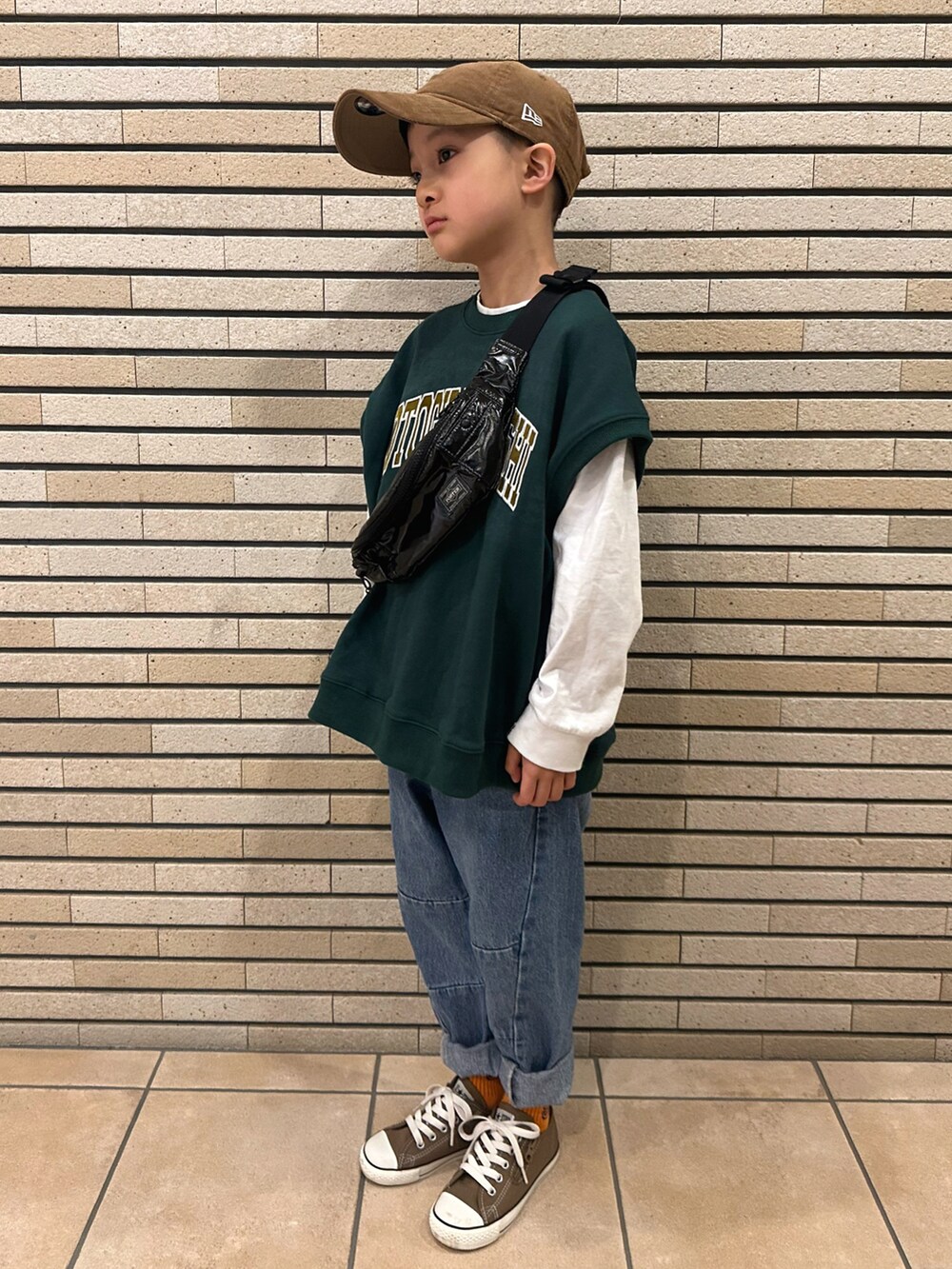 グリーン系のベスト、ホワイト系のTシャツ/カットソー、ブルー系のデニムパンツを着用したキッズの春コーディネートの2枚目の写真