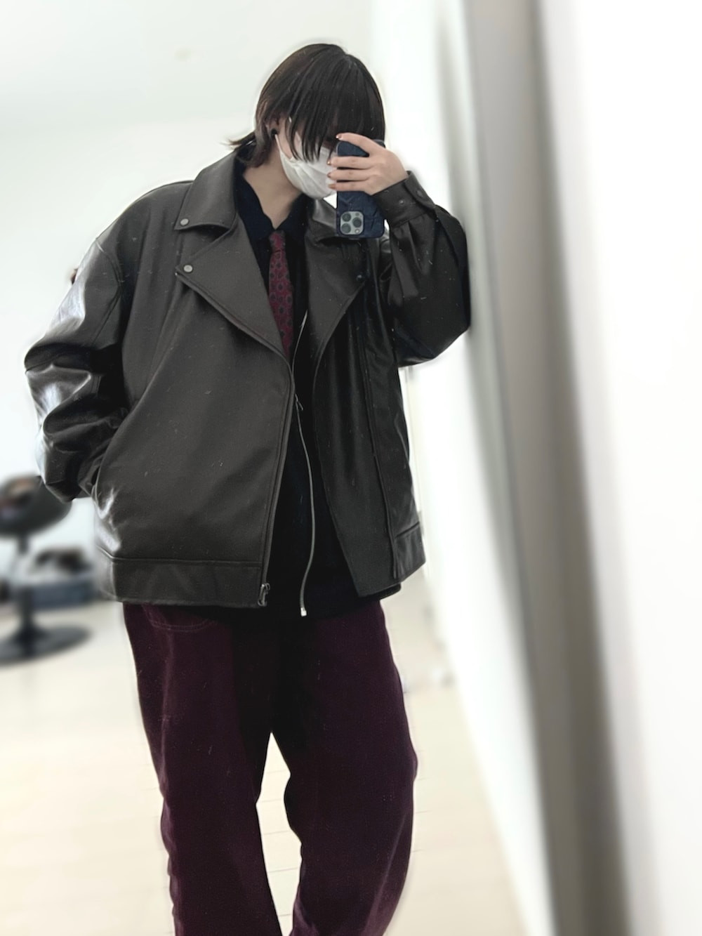 ブラウン系のライダースジャケット、レッド系のデニムパンツ、レッド系のネクタイを着用したレディースの冬コーディネートの2枚目の写真