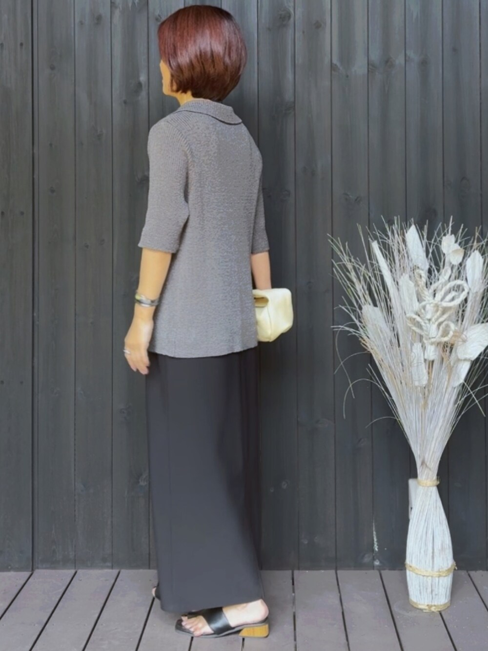 グレー系のカーディガン/ボレロ、ブラック系のワンピース、ブラック系のサンダルを着用したレディースの夏コーディネートの2枚目の写真