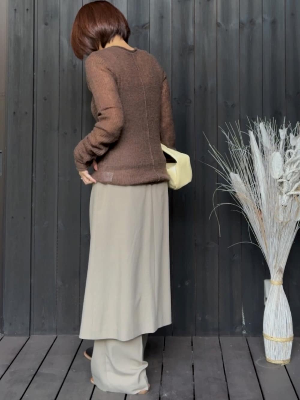 ブラウン系のニット/セーター、ベージュ系のハンドバッグ、ベージュ系のその他パンツを着用したレディースの夏コーディネートの2枚目の写真