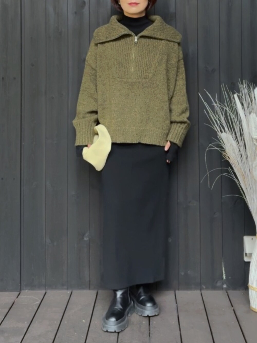 グリーン系のニット/セーター、ブラック系のワンピース、ベージュ系のハンドバッグを着用したレディースの秋コーディネートの2枚目の写真