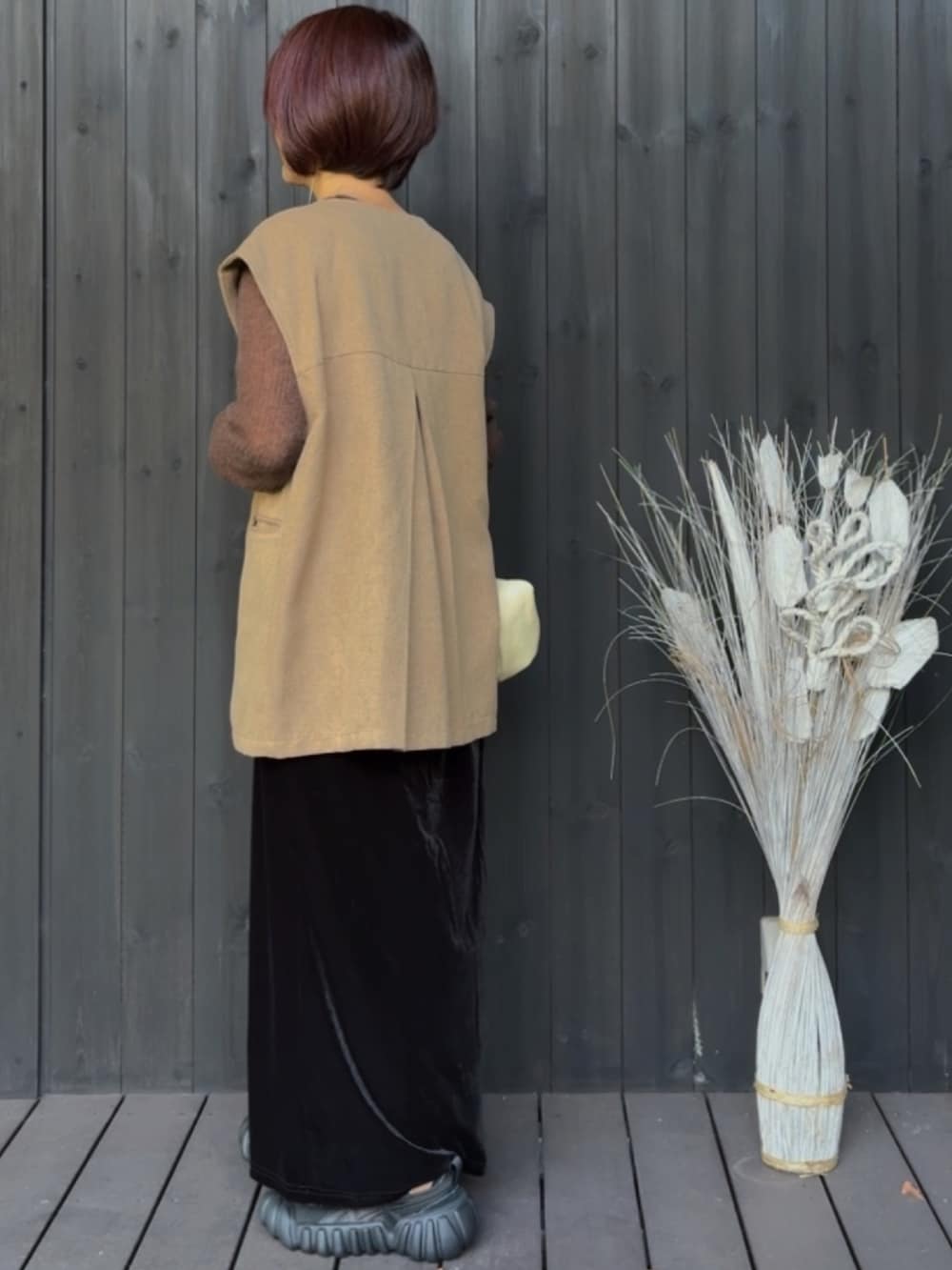 グリーン系のベスト、ブラウン系のニット/セーター、ブラック系のスカートを着用したレディースの秋コーディネートの2枚目の写真