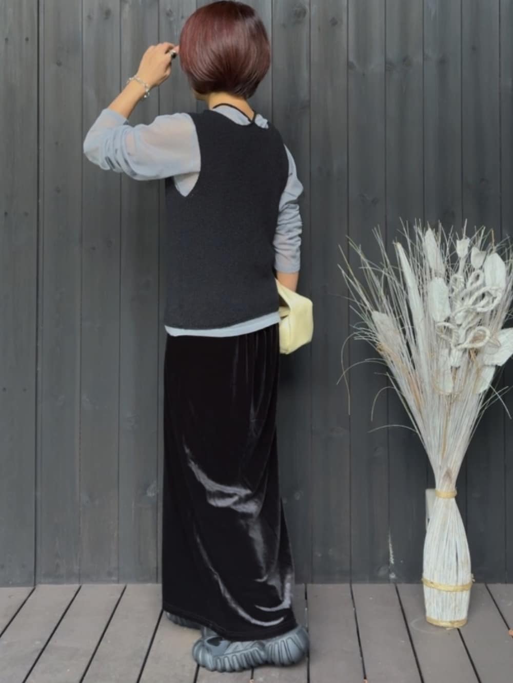 ブラック系のベスト、グレー系のニット/セーター、ブラック系のスカートを着用したレディースの秋コーディネートの2枚目の写真