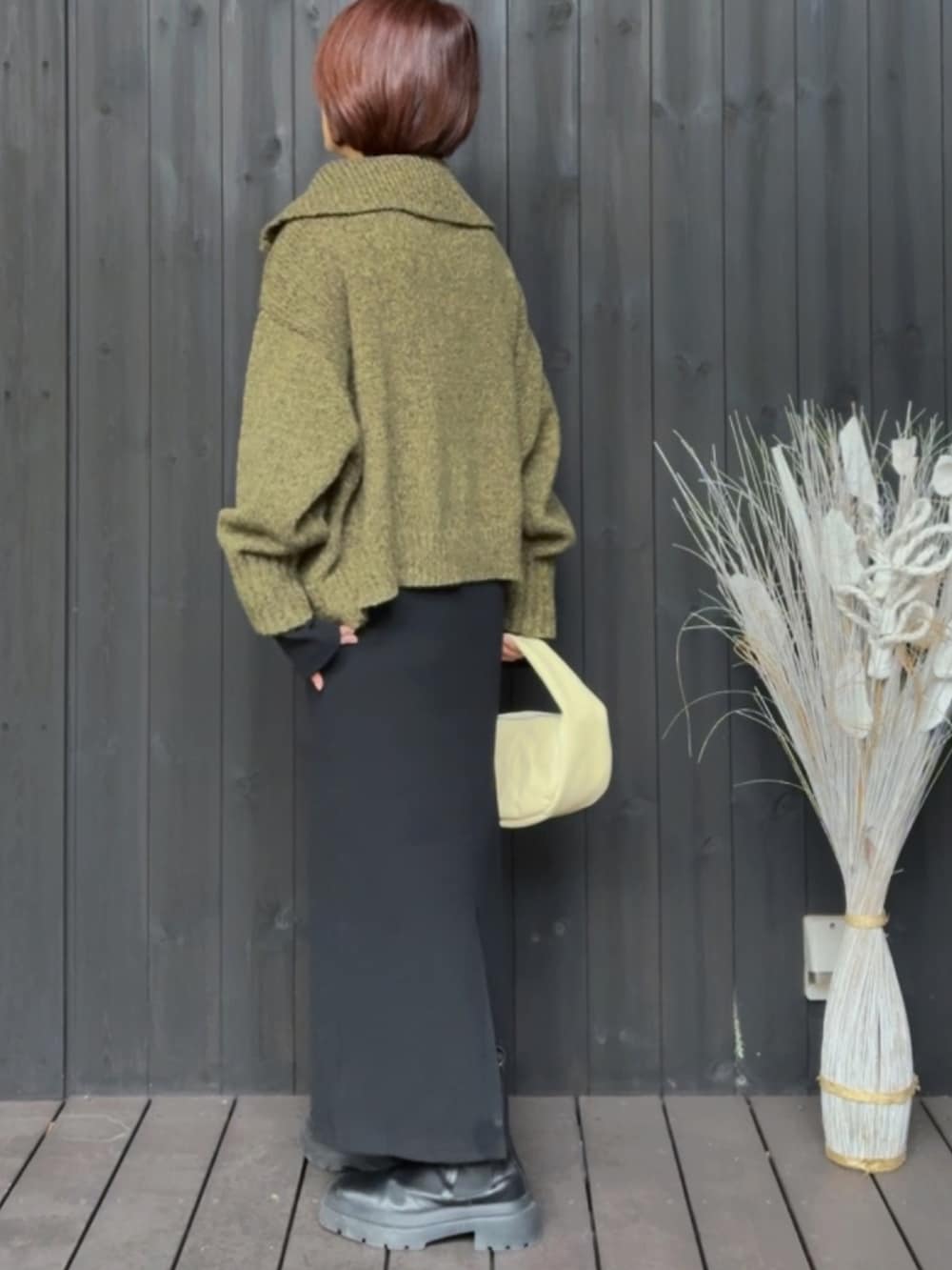 グリーン系のニット/セーター、ブラック系のワンピース、ベージュ系のハンドバッグを着用したレディースの秋コーディネートの3枚目の写真