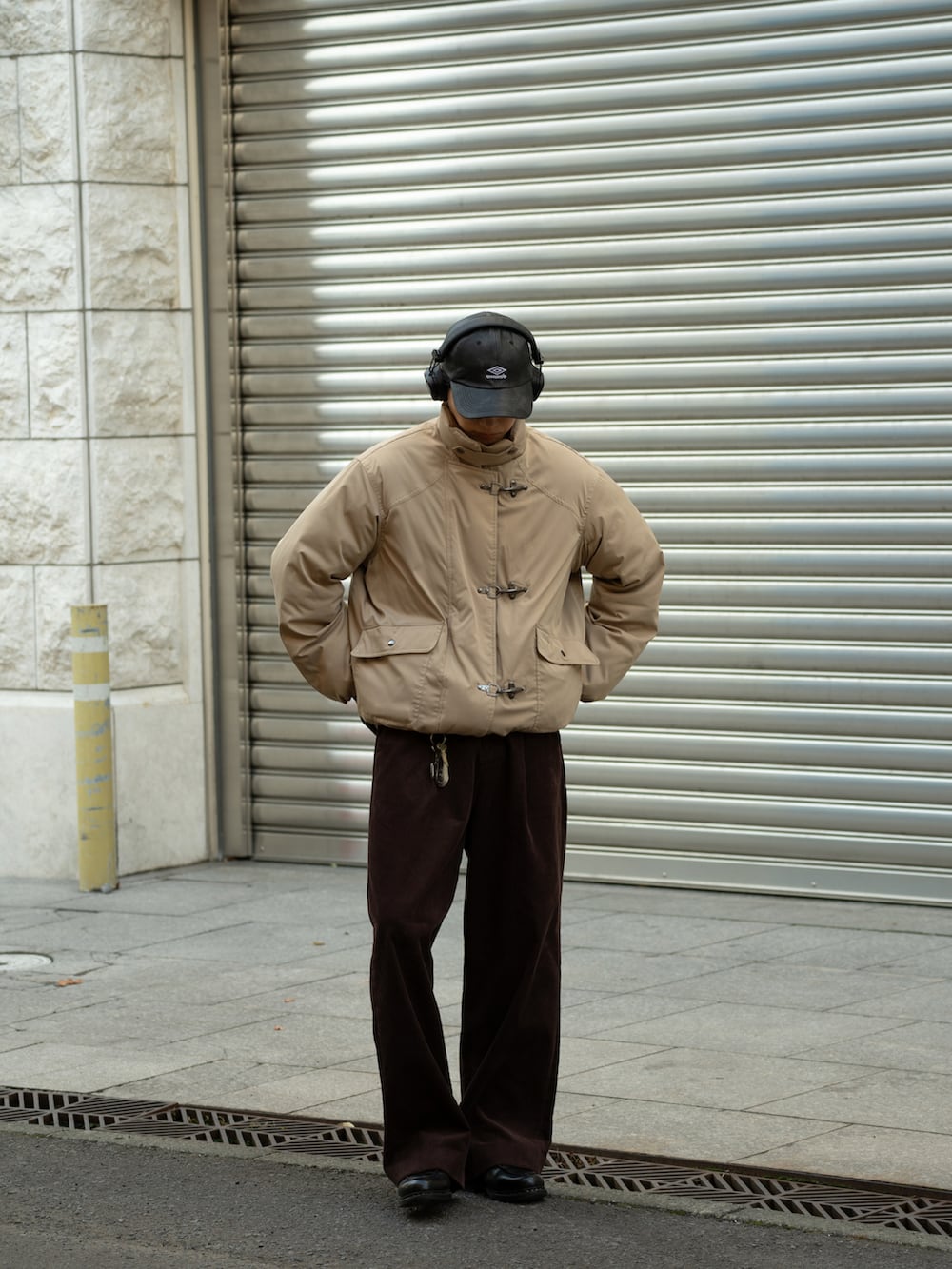 ベージュ系のダウンジャケット/コート、ブラウン系のスラックス、ブラック系のスウェットを着用したメンズの冬コーディネートの2枚目の写真