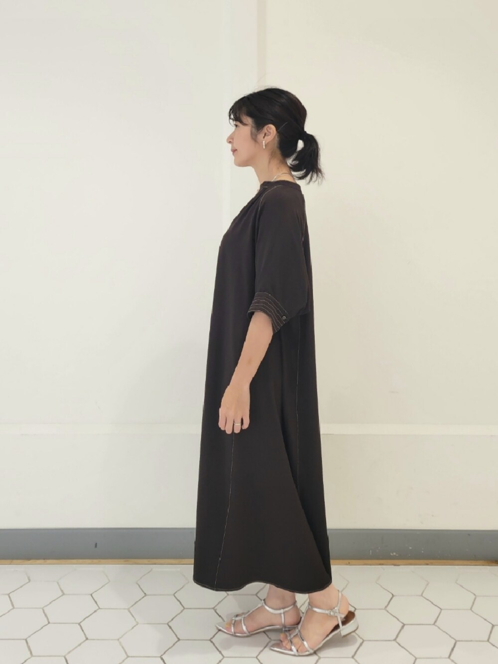 シルバー系のシューズ、ブラウン系のワンピース、ホワイト系のショルダーバッグを着用したレディースの春コーディネートの2枚目の写真